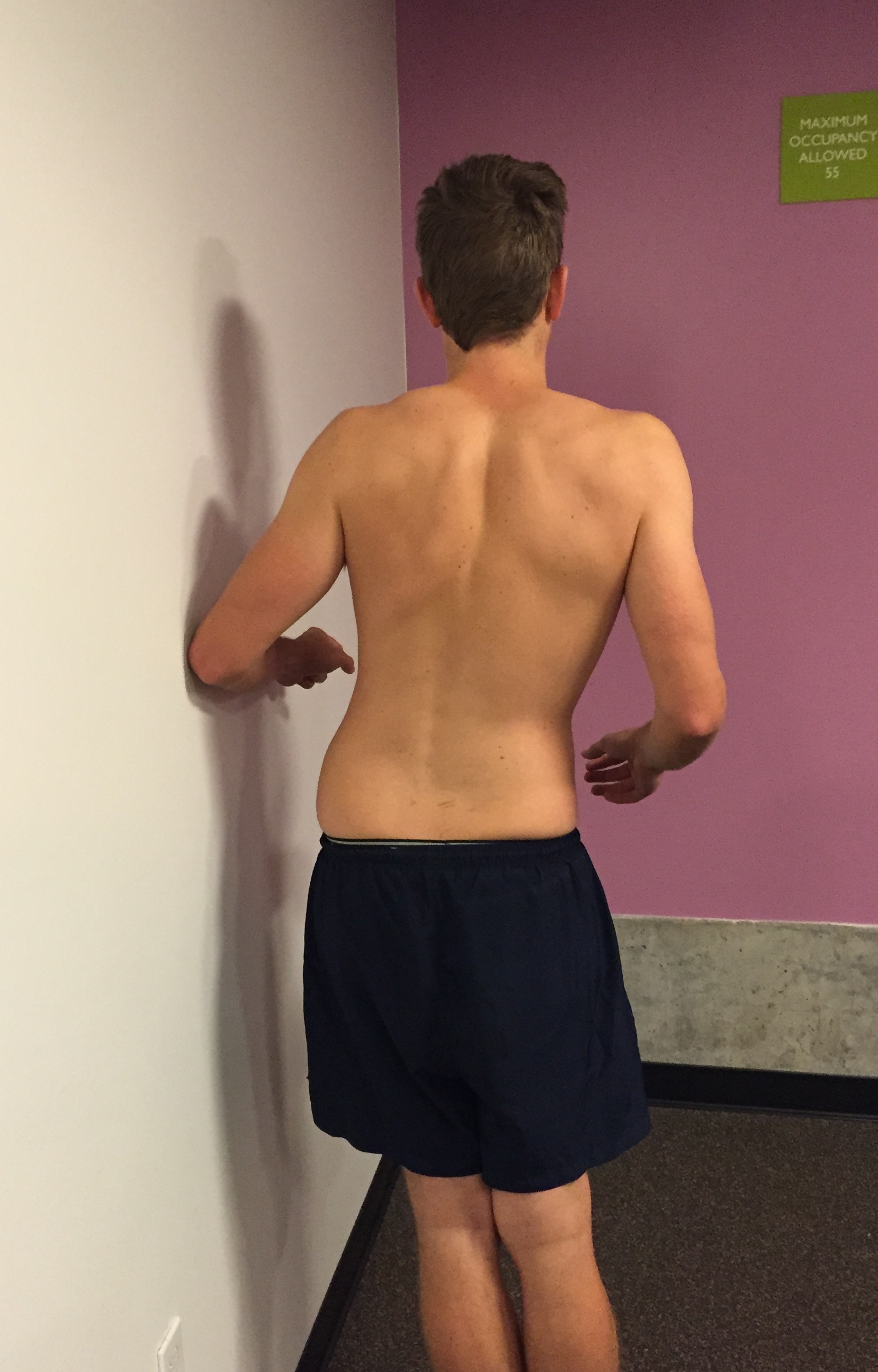By placing the elbow against the wall it supports the trunk and allows the side gliding movement to be localised to the lumbar spine. Ask the patient to move their hips towards the wall stopping at the first point or discomfort or pain. Often on Day 1 this is only completed on one side.
