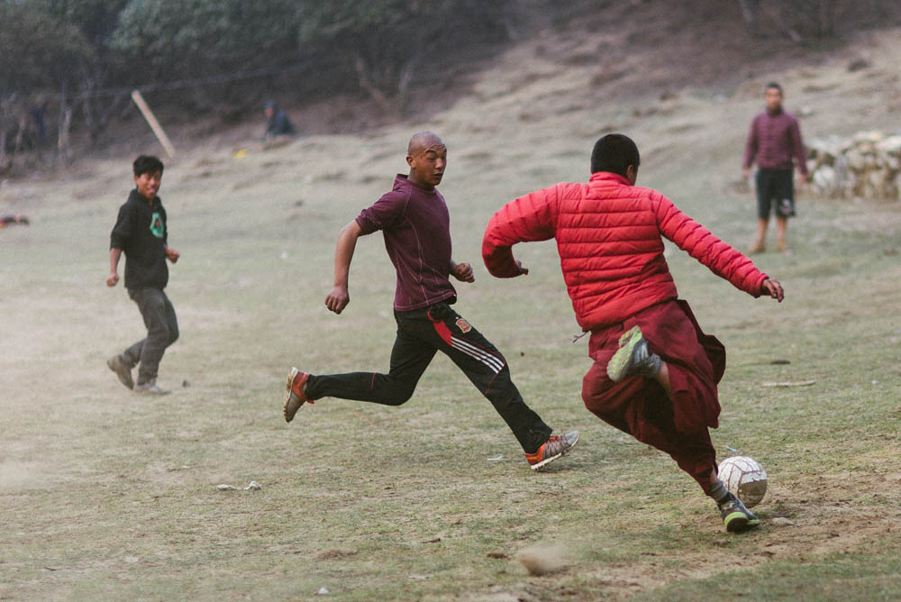 Tibetan monks enjoying a round of soccer with local porters and tourists.