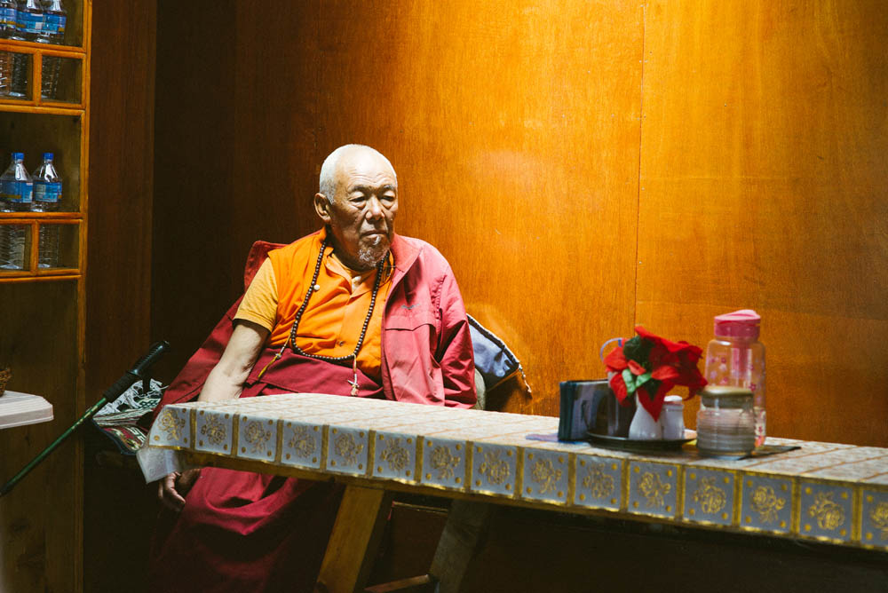 Tibeten monk resting under the light by the dinner tables. 
