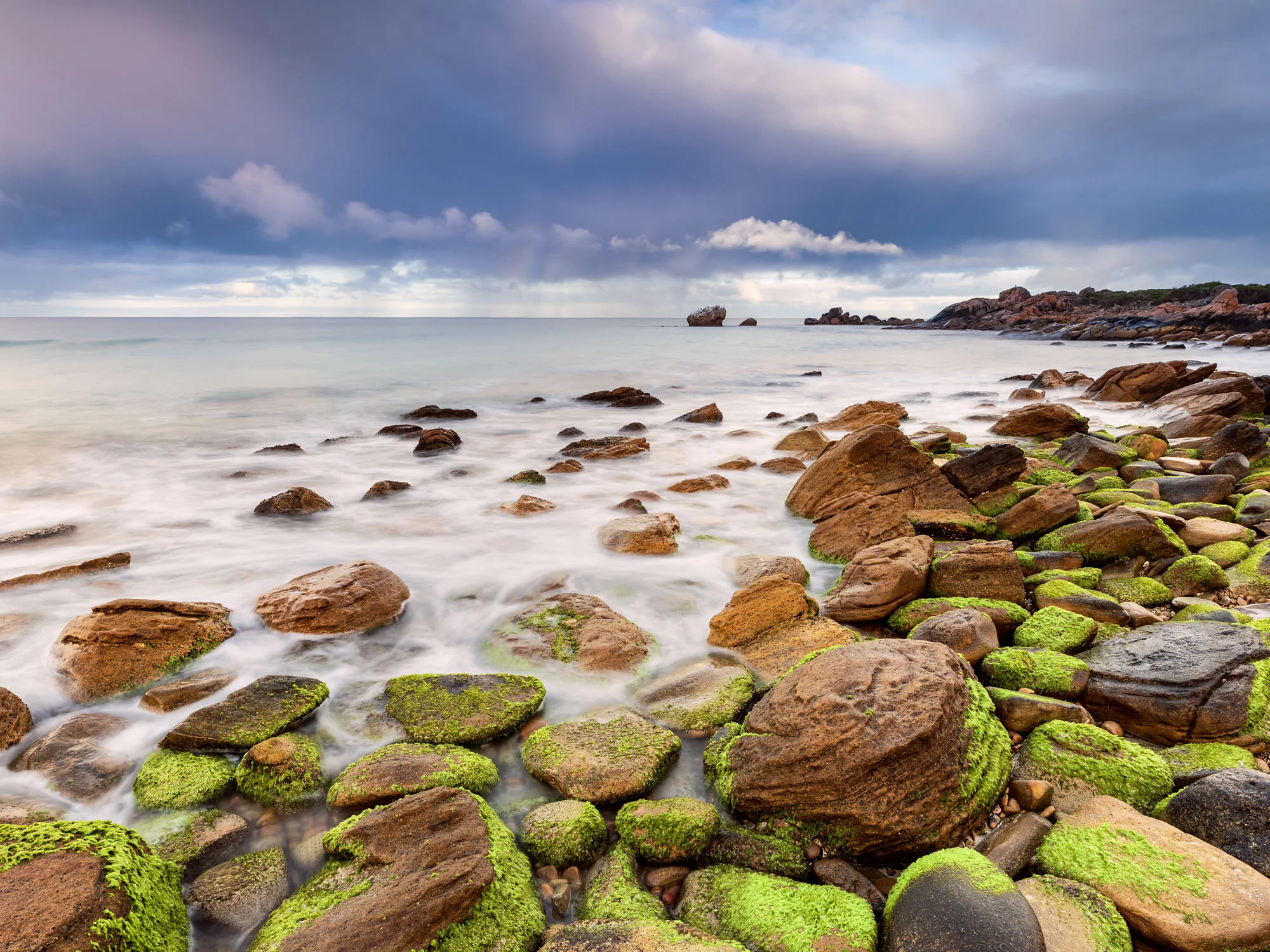 Mossy foreshore and rocks with stormy skies.