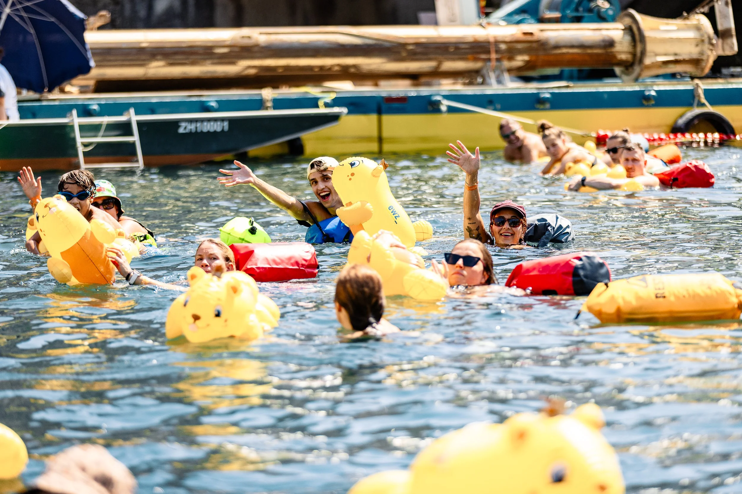 Limmatschwimmen Zürich: smiling swimmers with a yellow inflatable duck and a red dry bag / Lachende Schwimmende mit gelber Gummiente und rotem Wickelfisch