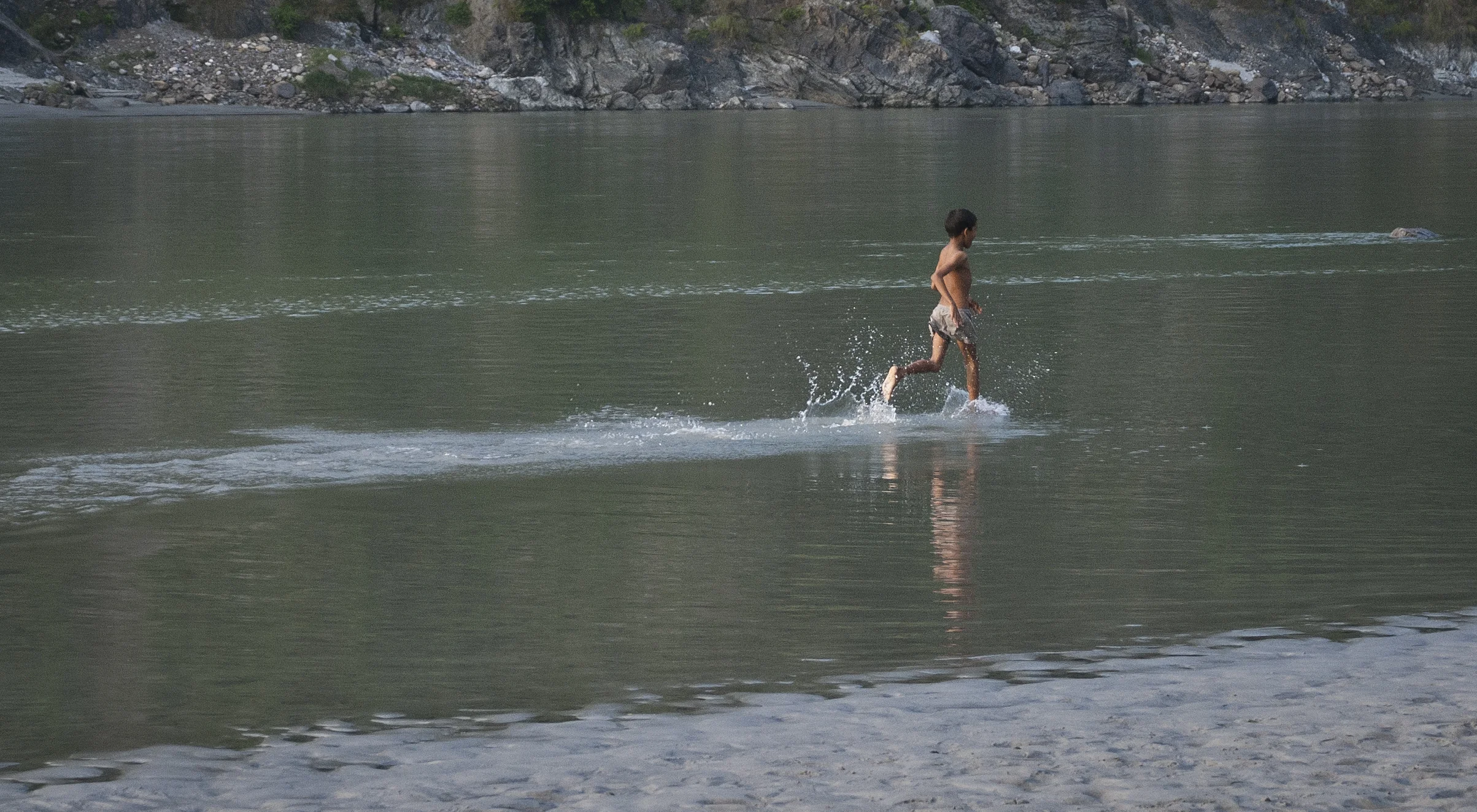 Boy running and playing in the Ganges