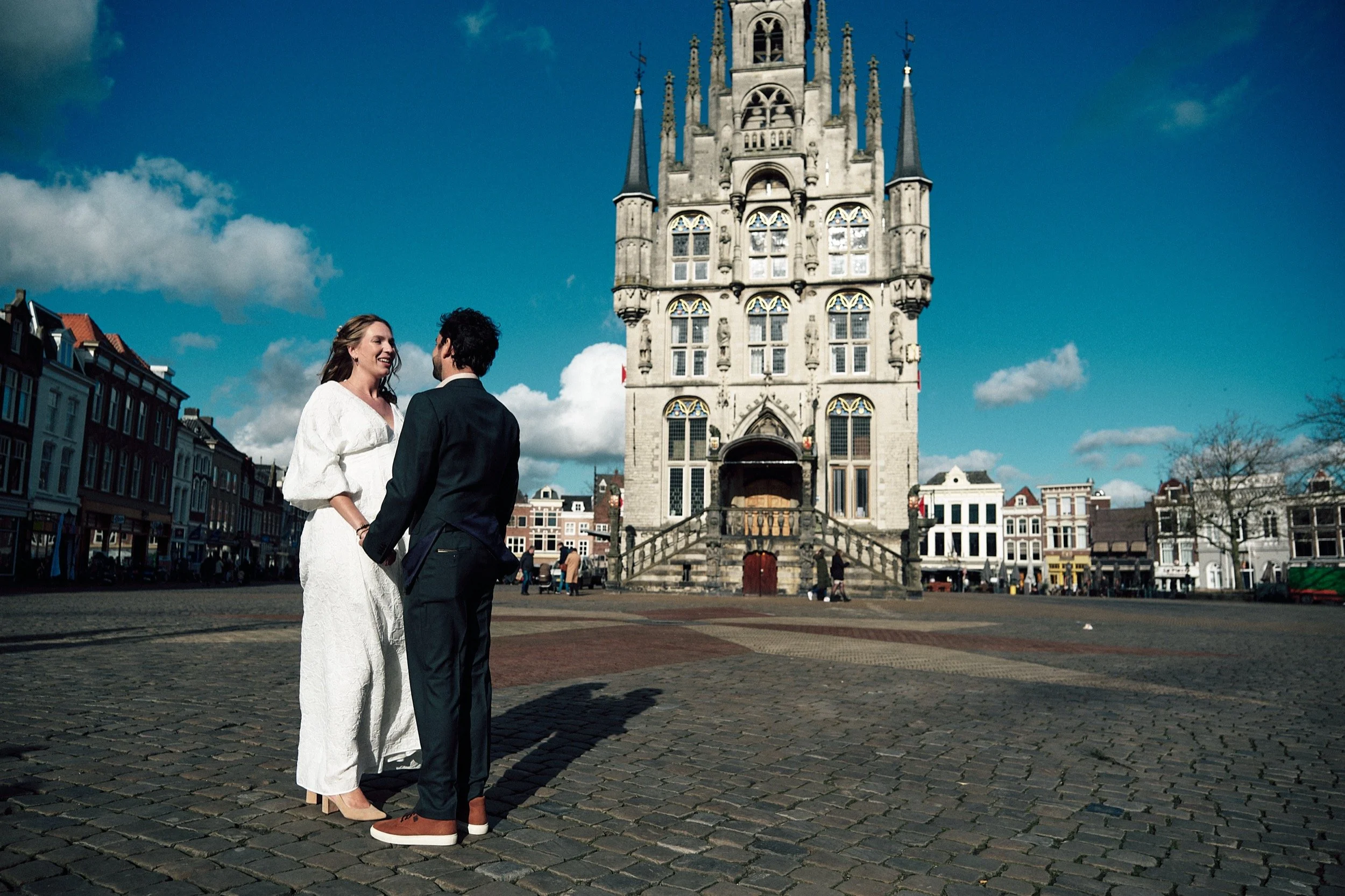 Voor het stadhuis van Gouda een bruidspaar op weg voor de ceremonie