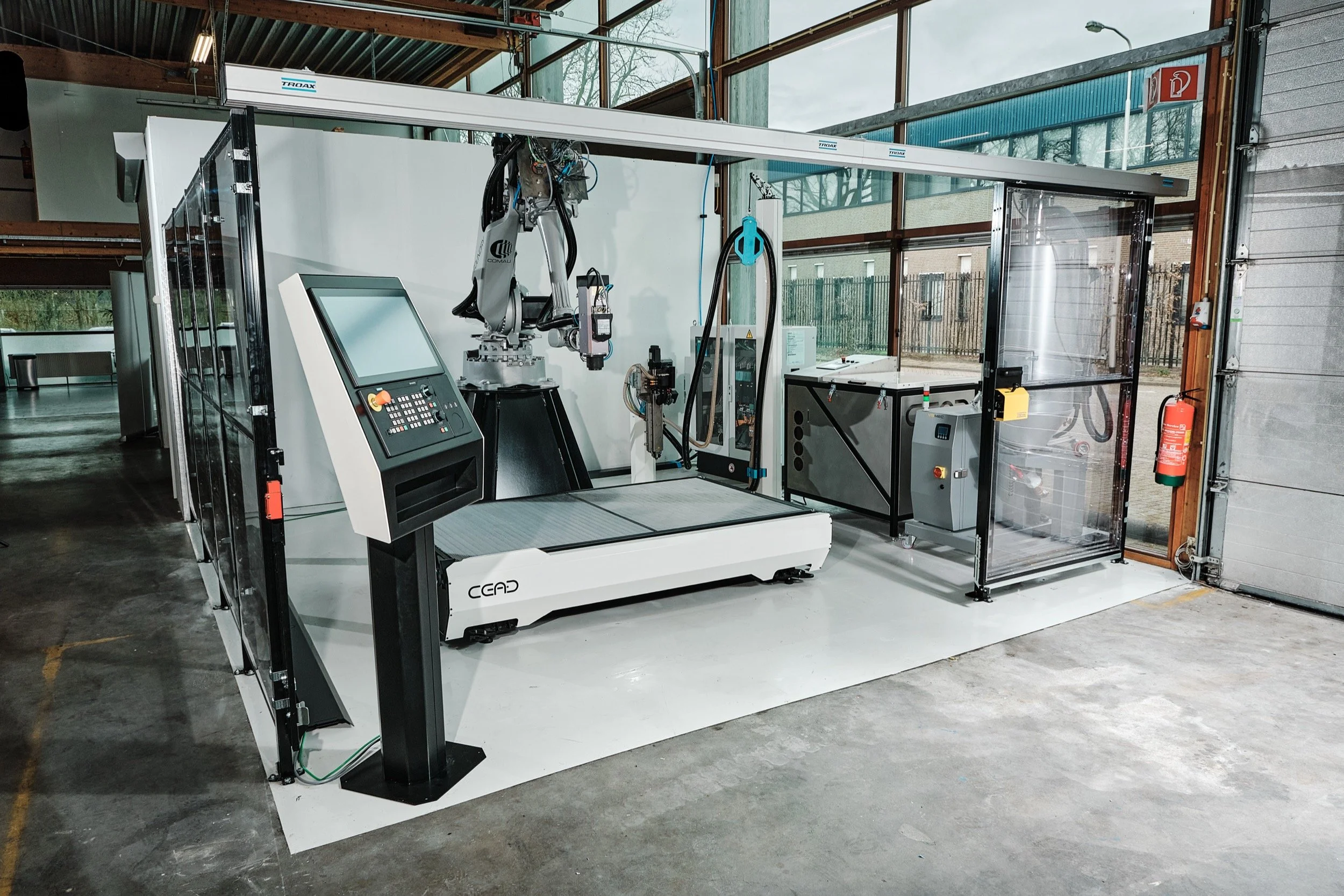Een geavanceerde robotarm met een CNC-machine en controlepaneel in een industriële werkomgeving.