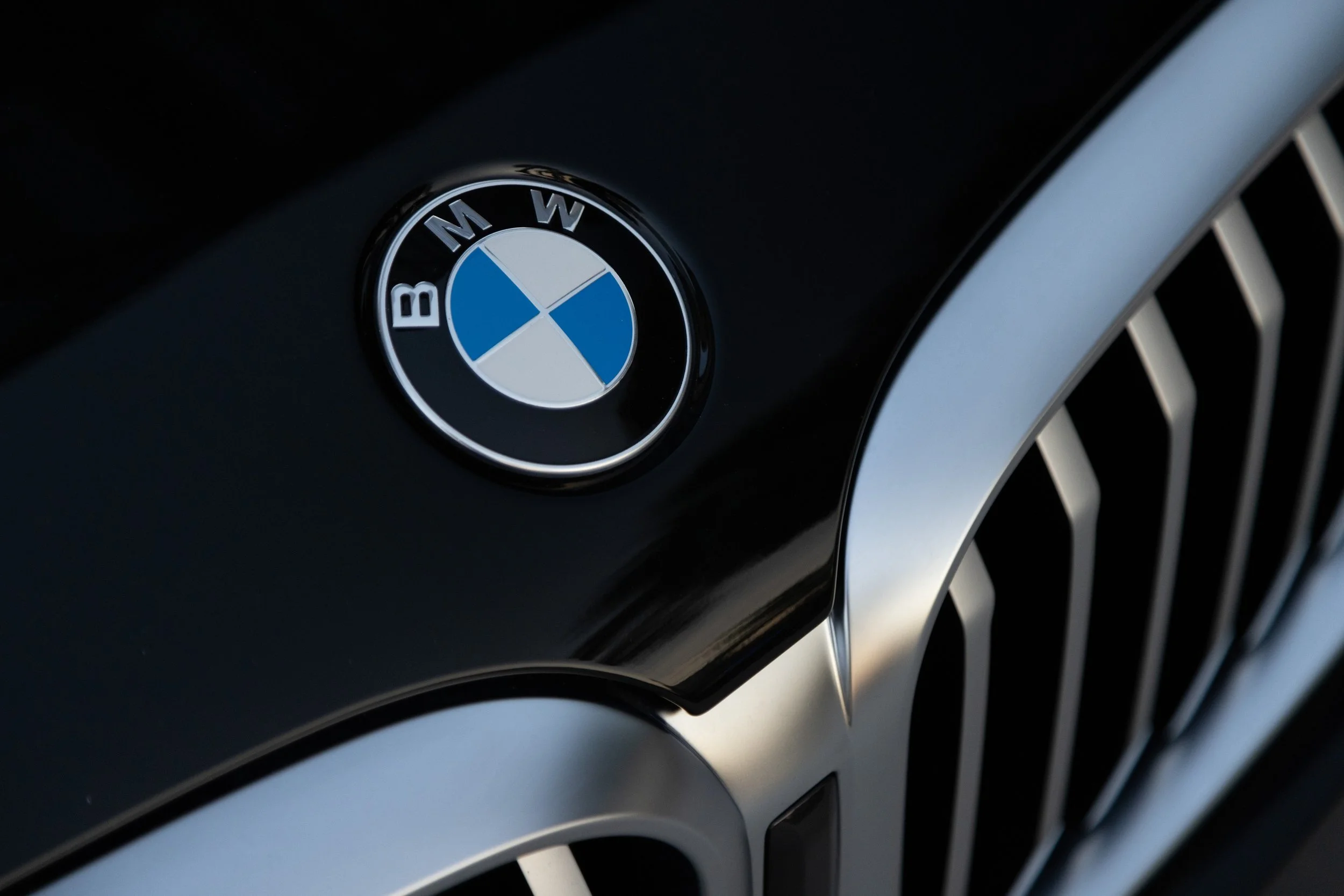Close-up of a BMW logo on the front grille of a black car.