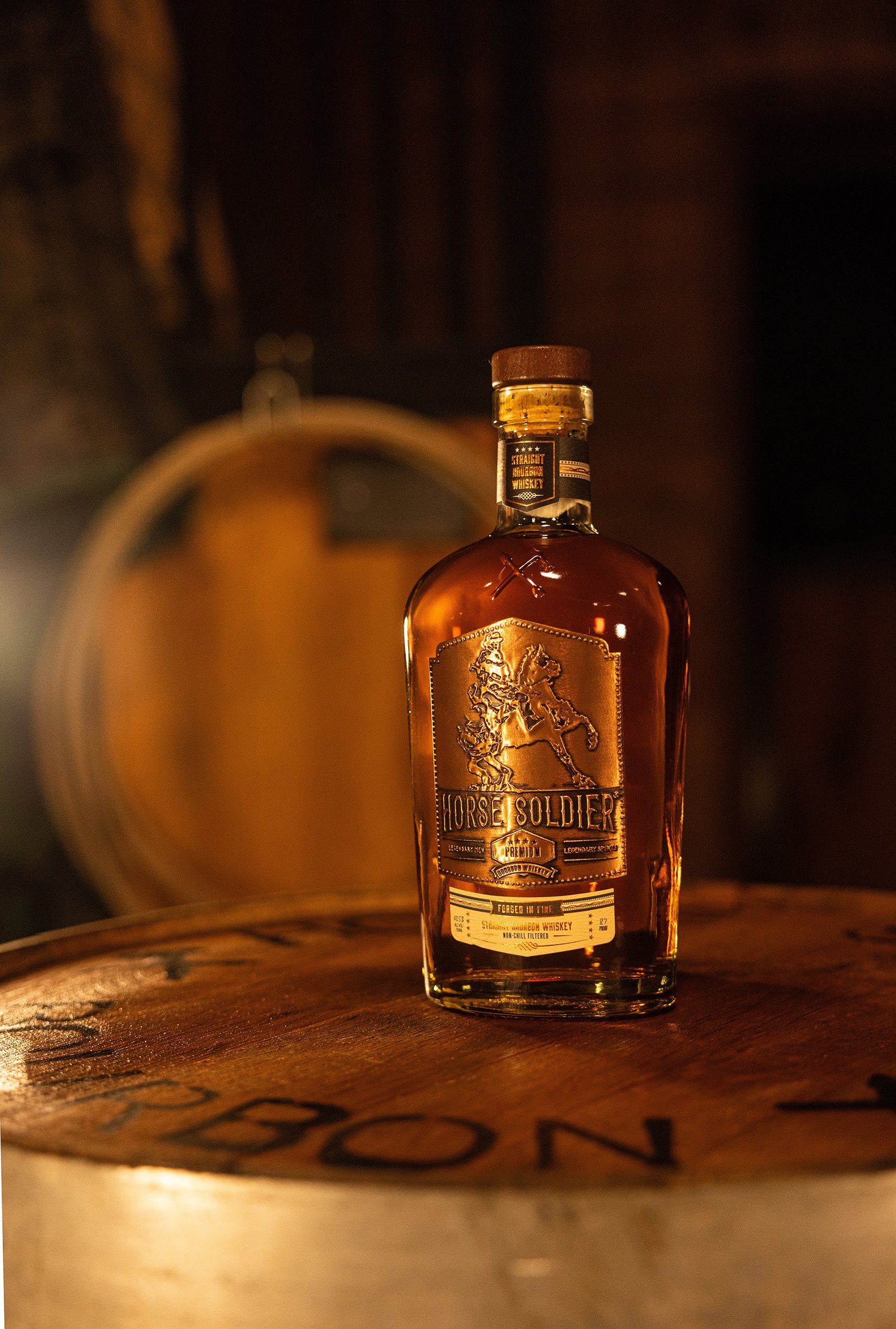A bottle of Horse Soldier bourbon whiskey on a wooden surface with a warm, dimly lit background.
