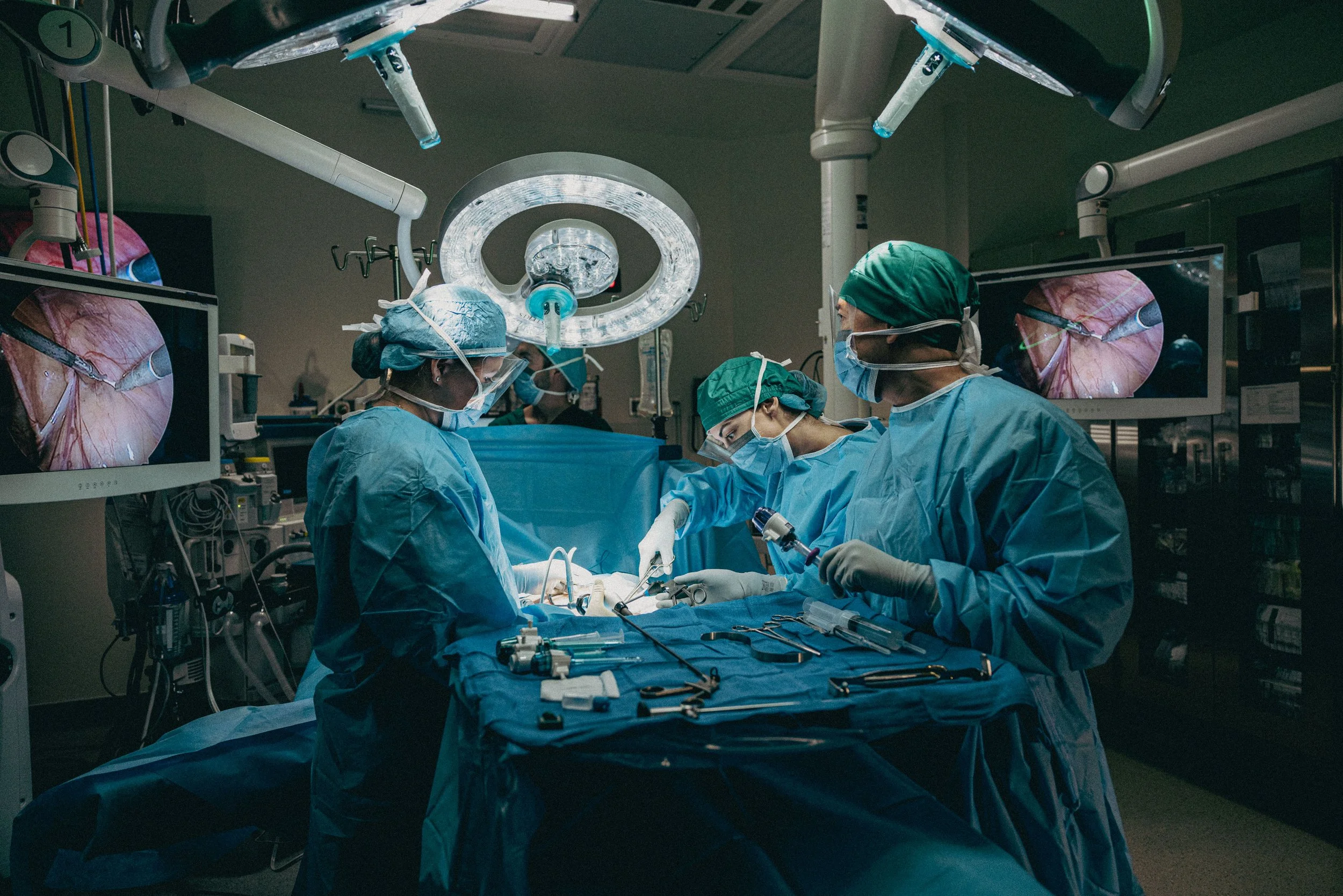 A team of surgeons operating in an operating room with medical monitors and equipment.