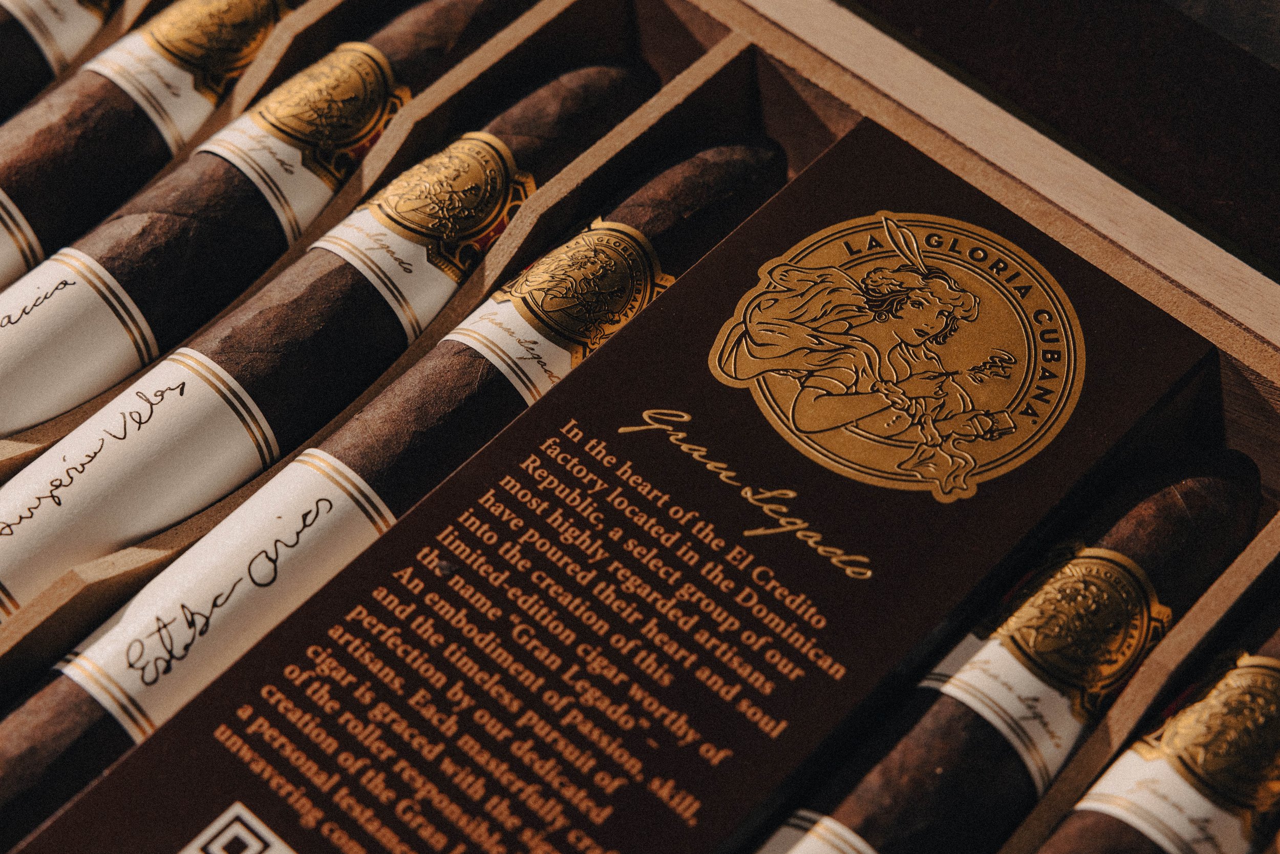 Close-up of cigars with a dark brown and gold label, displaying the brand La Gloria Cubana and a paragraph of text describing the brand's history and significance.