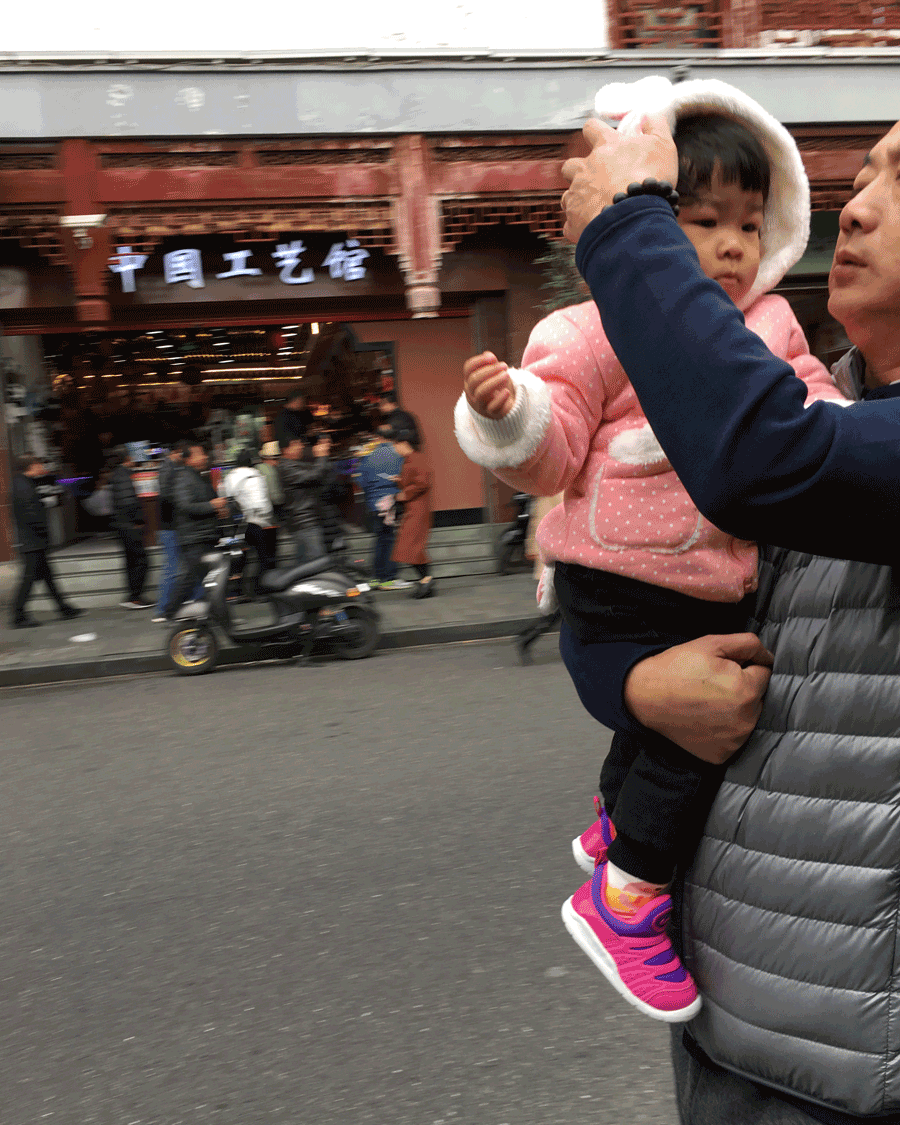 '' © Naida Ginnane 2017 iPhone 6. f/2.2, 1/100, ISO 25 This shot is a great example of how usual technical considerations are ignored in street photography. The background is blurred and the subject is cut off, but we still get the idea that things are busy in that street and little girls always need costume adjustments.
