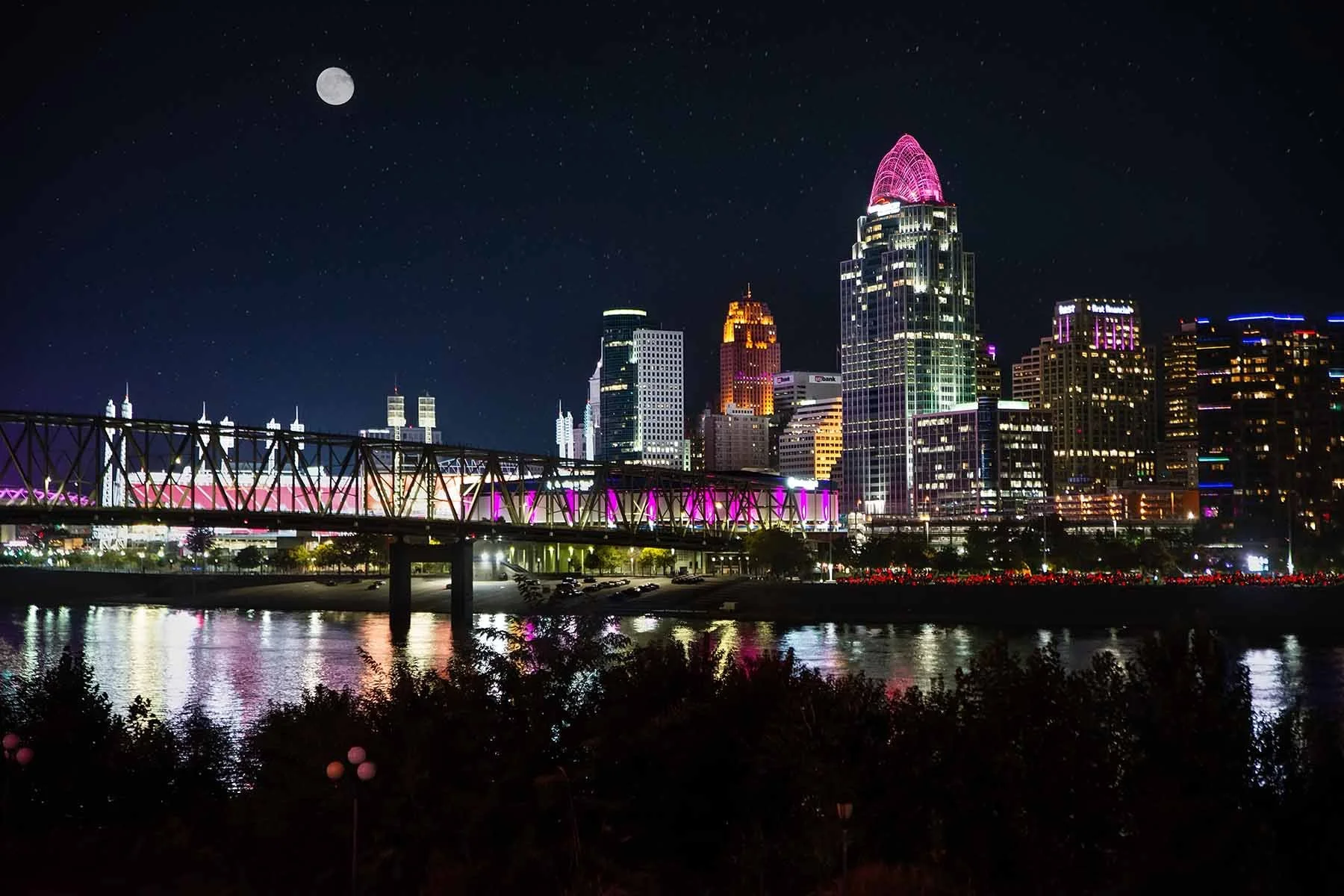 Night photo of the Cincinnati skyline during Light Up Cincinnati, with downtown towers and riverfront buildings illuminated against the dark sky.