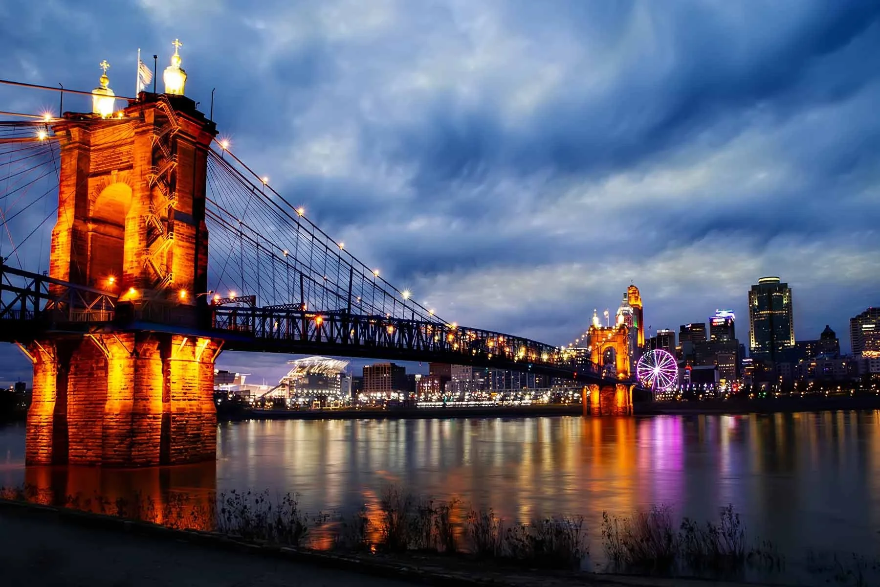 John A. Roebling Suspension Bridge in Cincinnati photographed at blue hour, the bridge and Cincinnati skyline silhouetted in the cool light after sunset.