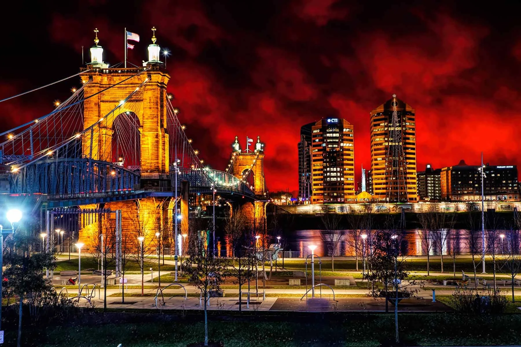 Nighttime fine art photo of the John A. Roebling Bridge from the Cincinnati riverfront, with the suspension span silhouetted against a vivid red sky by photographer Ed Taylor