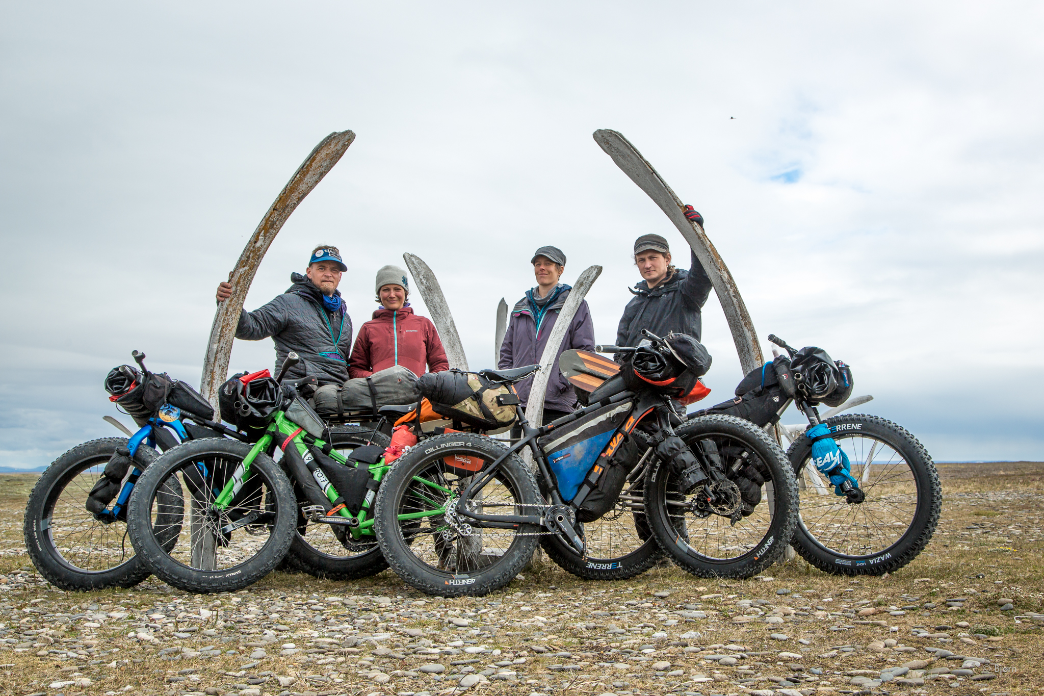 Bjørn Olson, Alayne Tetor, Kim McNett and Daniel Countiss pause in front of a whale bone yard in Point Hope before beginning their fat-bike traverse of the Arctic. 