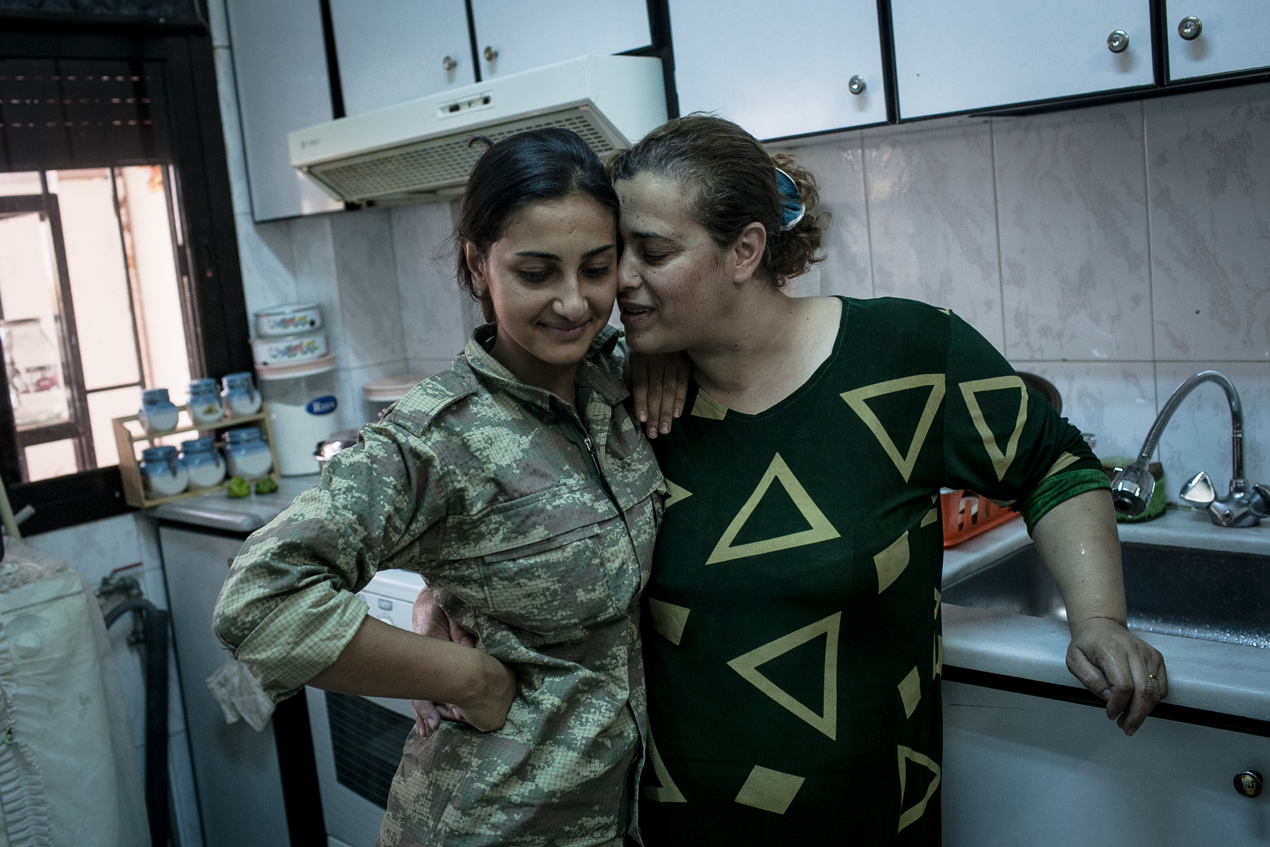  Jin, left, a YPJ soldier, is hugged by her mother, Amina, at their home in Girke Lege, Syria. Although she lives at a YPJ base near her mother’s home, Jin had not seen her mother in months because of the YPJ’s demanding training schedule. 