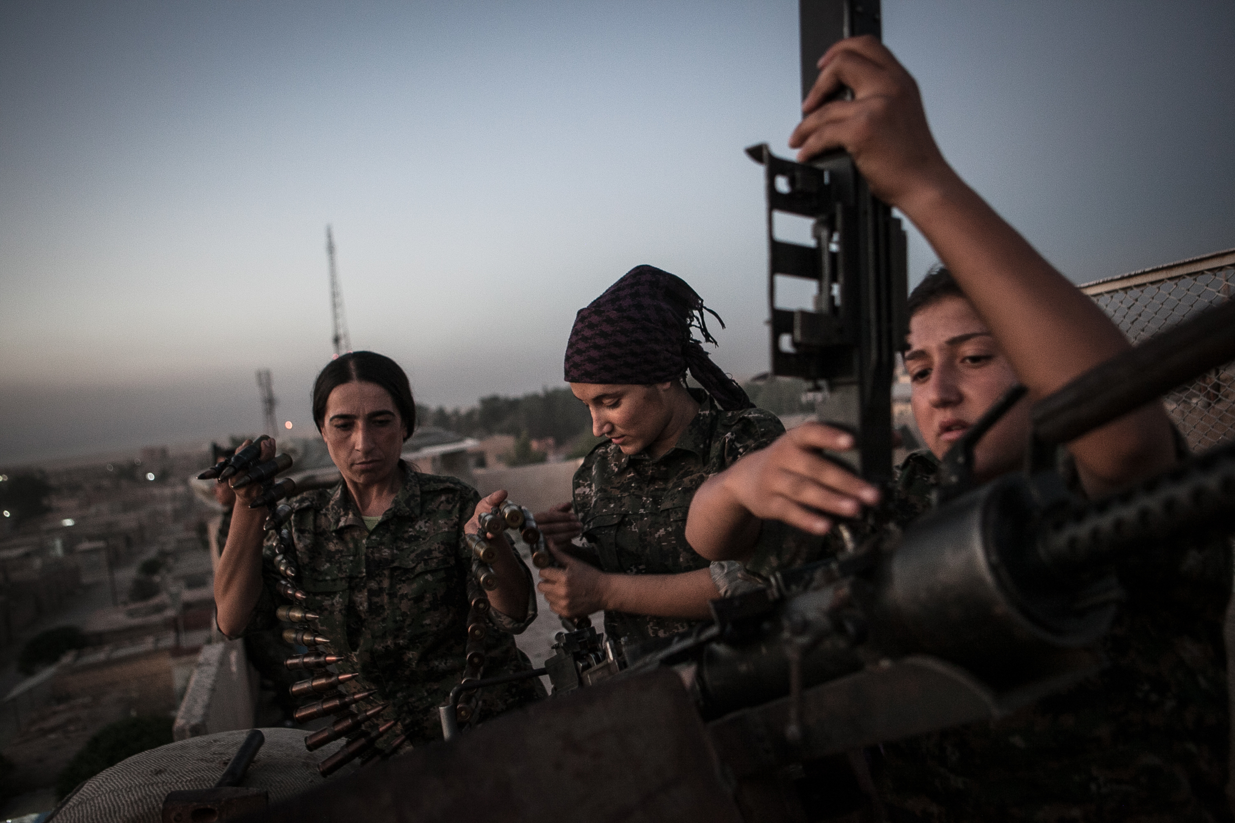 Captain Ronahi Anduk, 34, left, Gian Dirik, center, and Dirsim Judi, 18, right, fix the DShK weapon at a YPJ military base in Til Kocer, Syria. The DShK weapon is a Soviet machine gun typically used as an anti-aircraft wepaon, but the YPJ use it to 