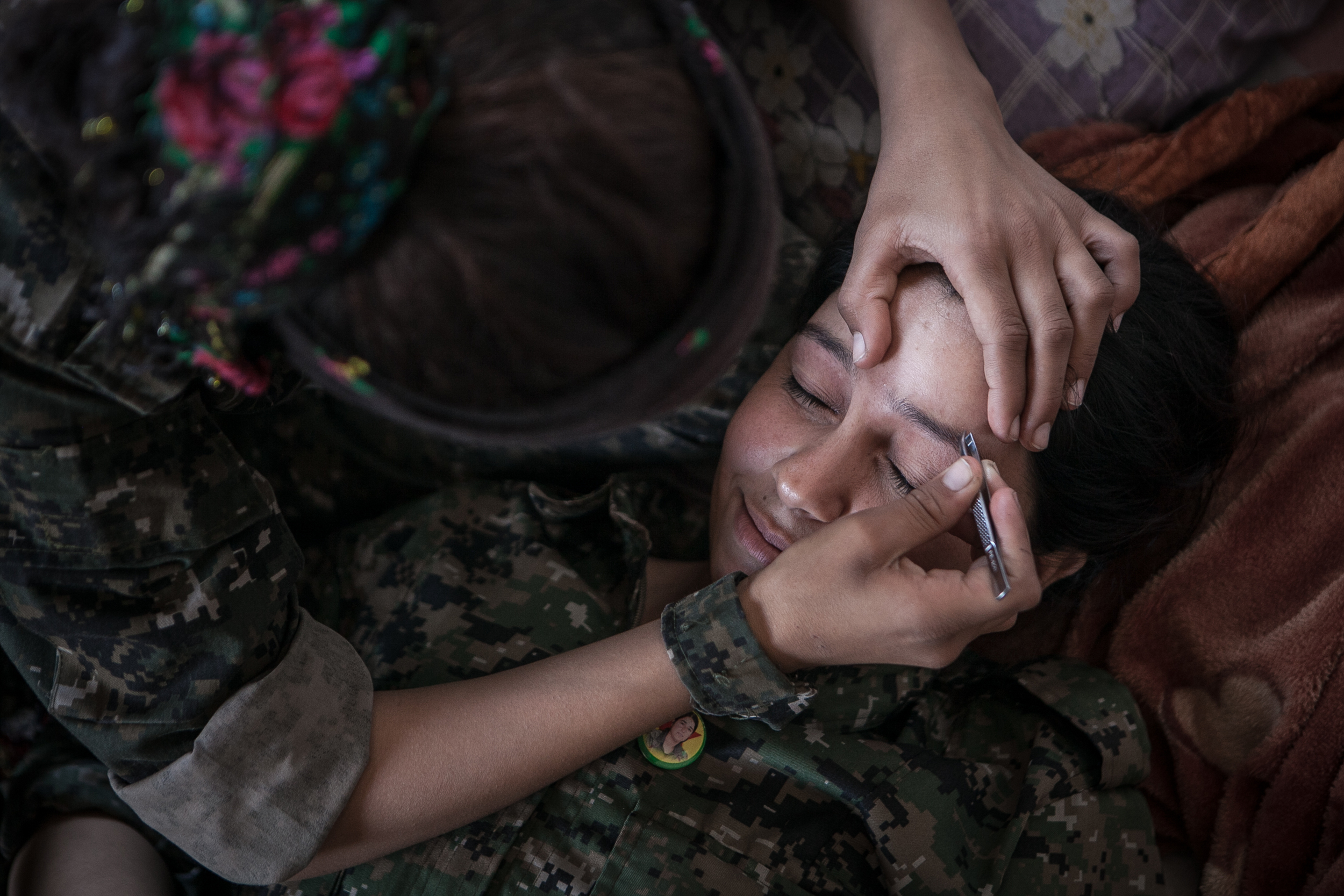  Azadi Qamishlo, 22, has her eyebrows plucked by a fellow soldier at a YPJ military base in the town of Til Kocer, Syria.  