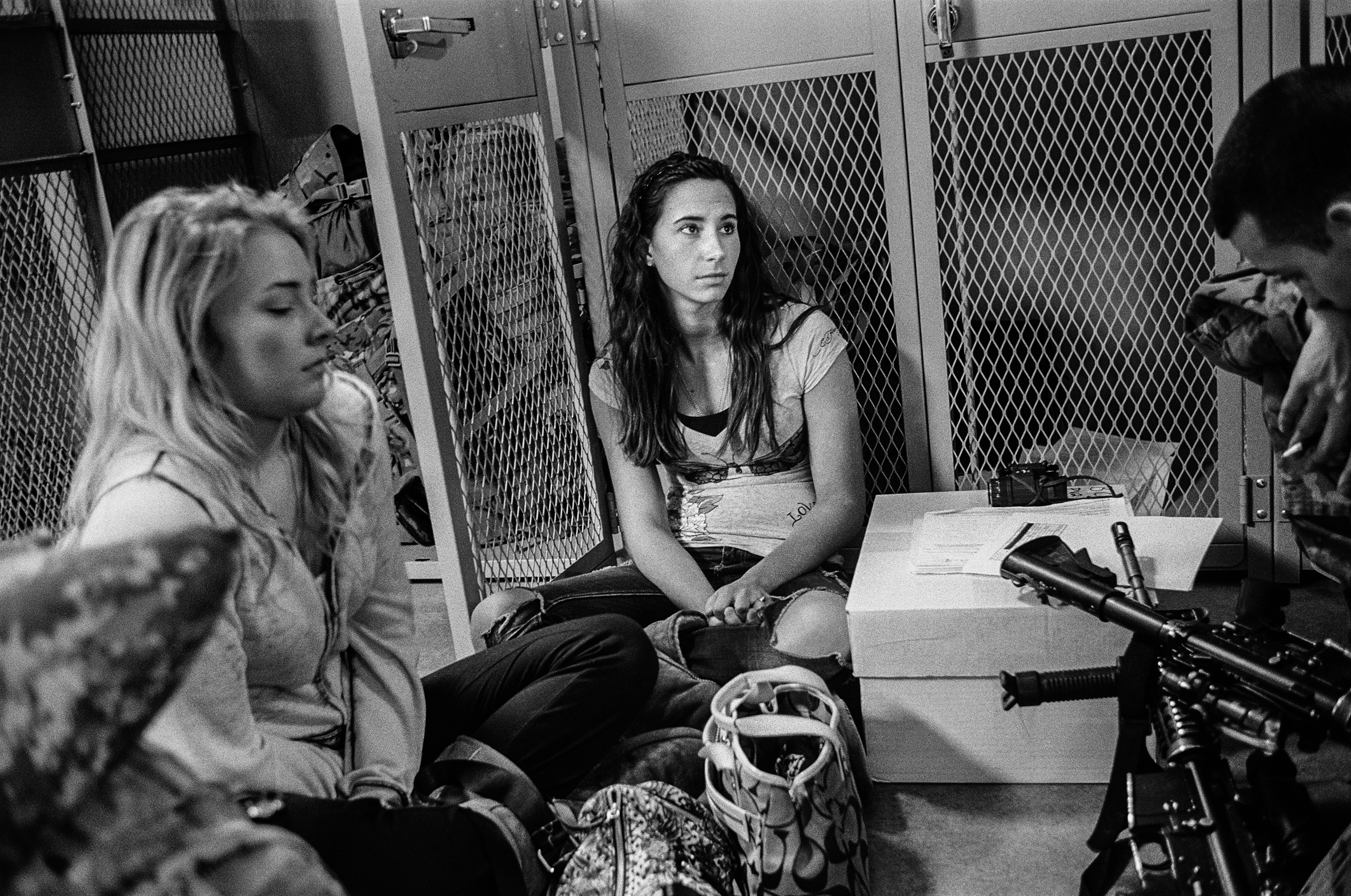  A young woman sits quietly in a locker room before her boyfriend deploys to Afghanistan at Fort Drum, New York, 2011. 