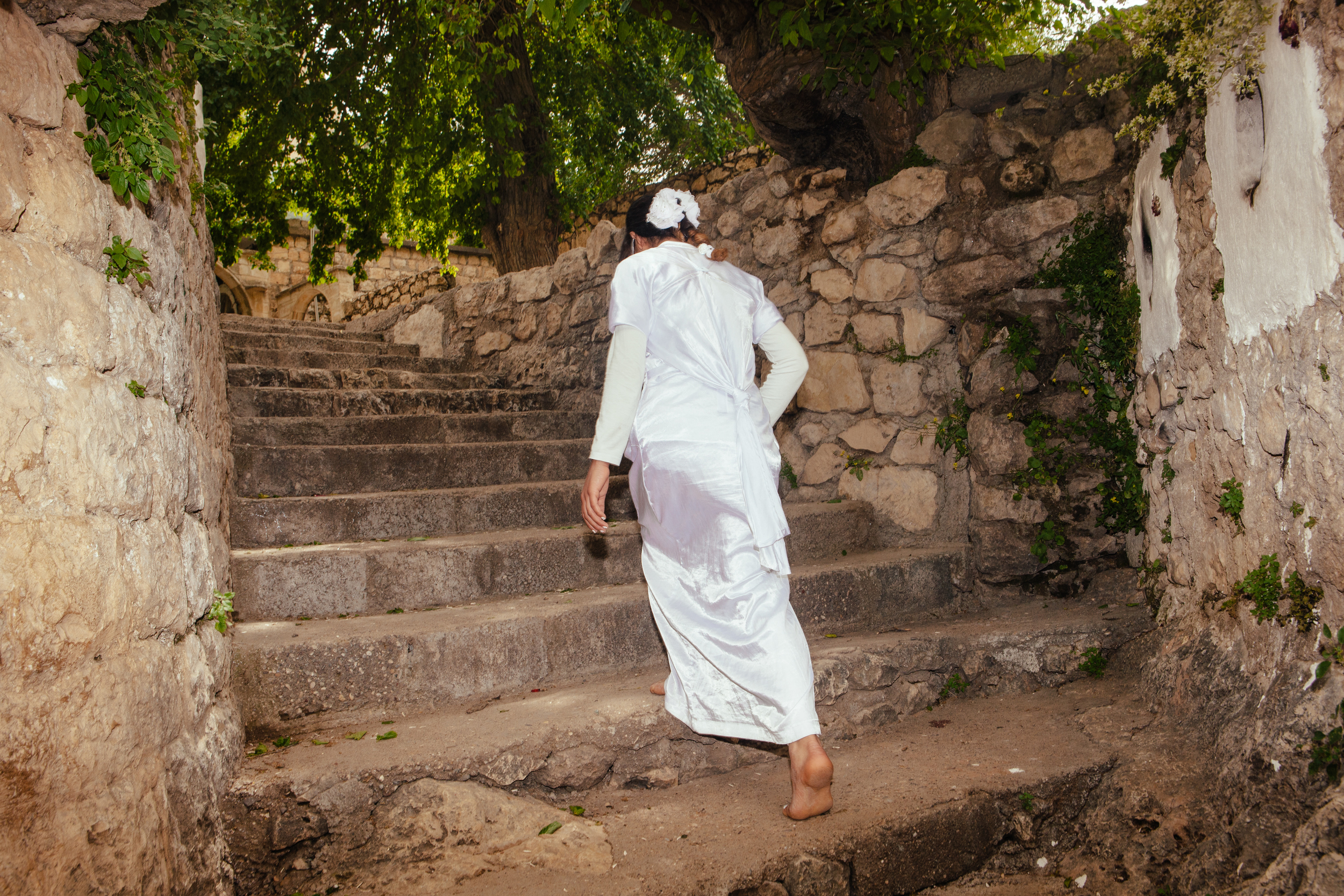  Sundis Ziad Hassan wears a white gown, a Yezidi tradition, as she walks to pray at the Lalish temple, the most sacred and only Yezidi temple in the world,&nbsp;Northern Iraqi Kurdistan. 