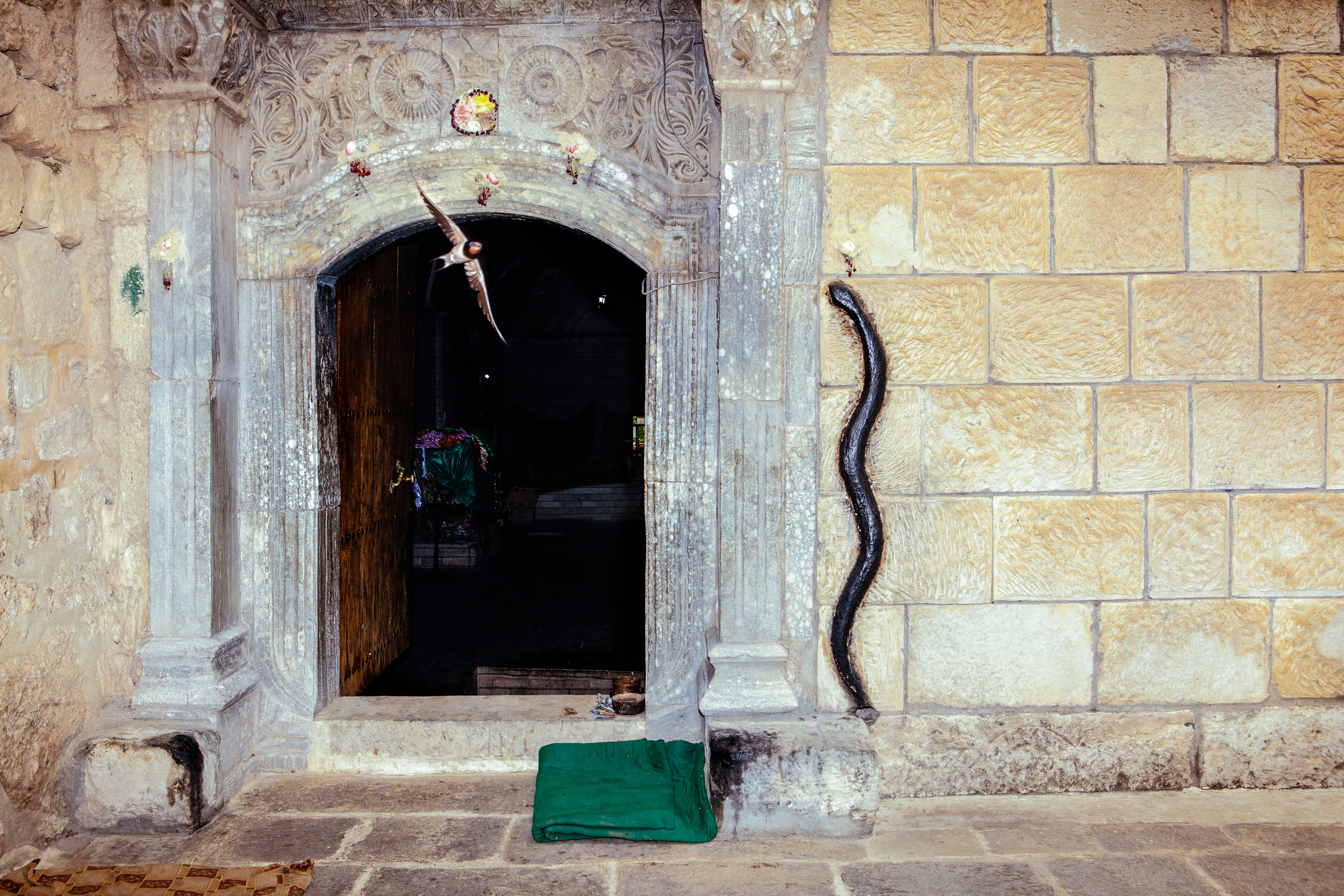  A bird flies out of Lalish temple which features a stone black snake on it's wall in Northern Iraqi Kurdistan. Lalish is the most sacred and only Yezidi temple in the world.&nbsp;According to legend, the snake was once a live serpent but was transfo