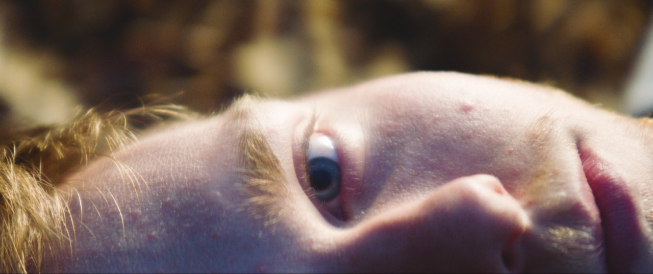 Close up picture of a teenage boy lying down and looking at the camera