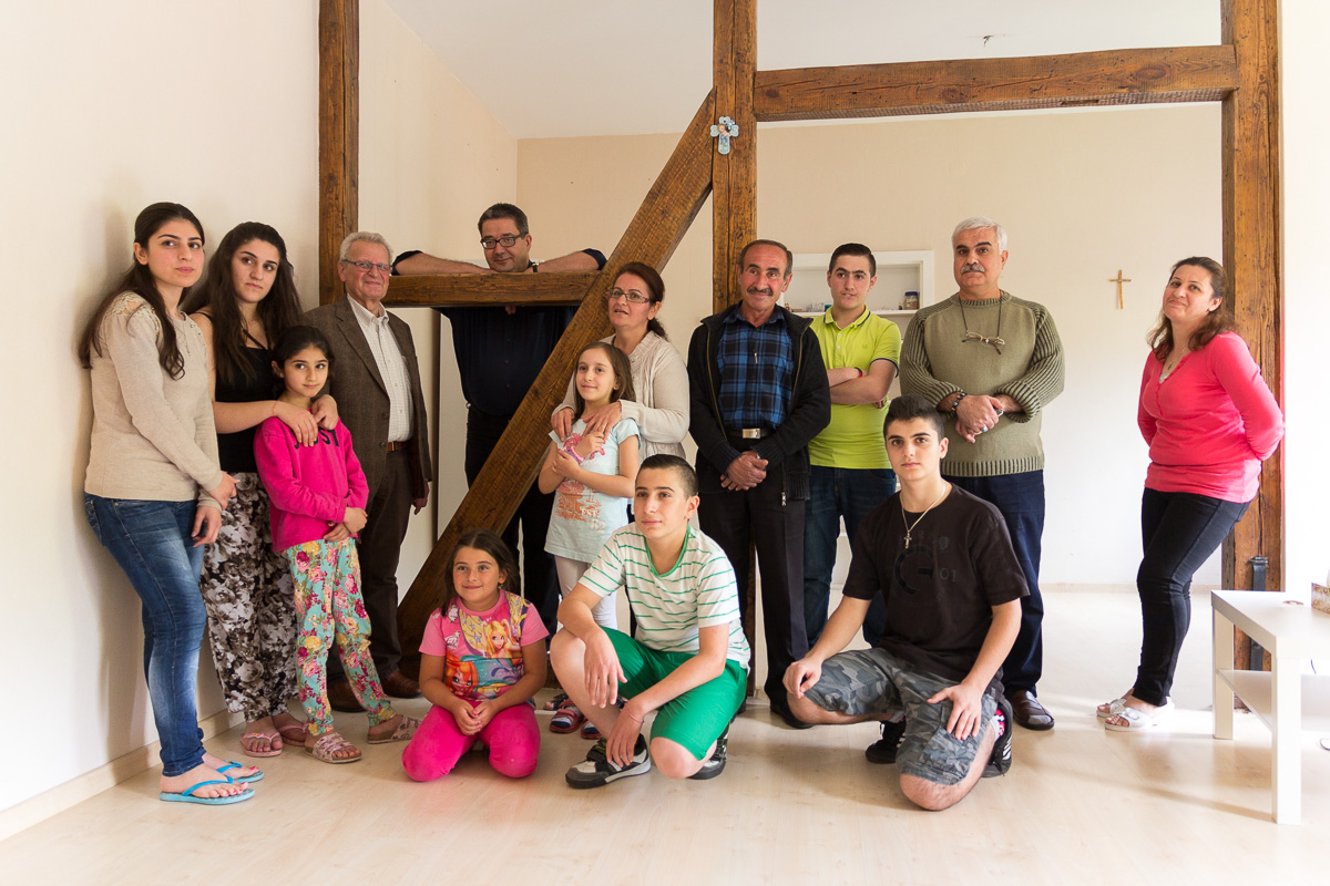 Die beiden syrischen Familien gemeinsam mit Verwaltungsrat Peter Lesko (4.v.l.) und Pfarrer Stephan Gras (ganz hinten) in der Wohnung am Kirchort St. Elisabeth. Foto: Benjamin Dahlhoff