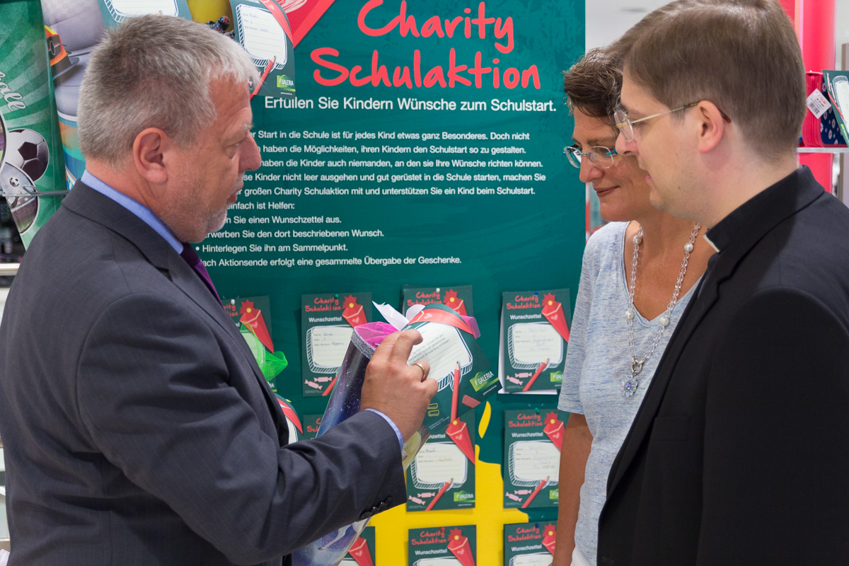 Filialgeschäftsführer Karsten Sinnig stellt Dr. Julia Fauth und Pfarrer Klaus Nebel die Schultüten im Erdgeschoss der Galeria Kaufhof vor.