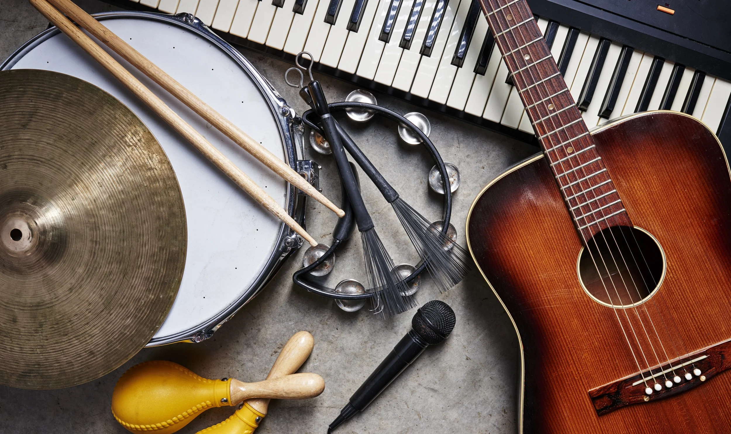 a group of musical instruments including a guitar, drum, keyboard, tambourine.