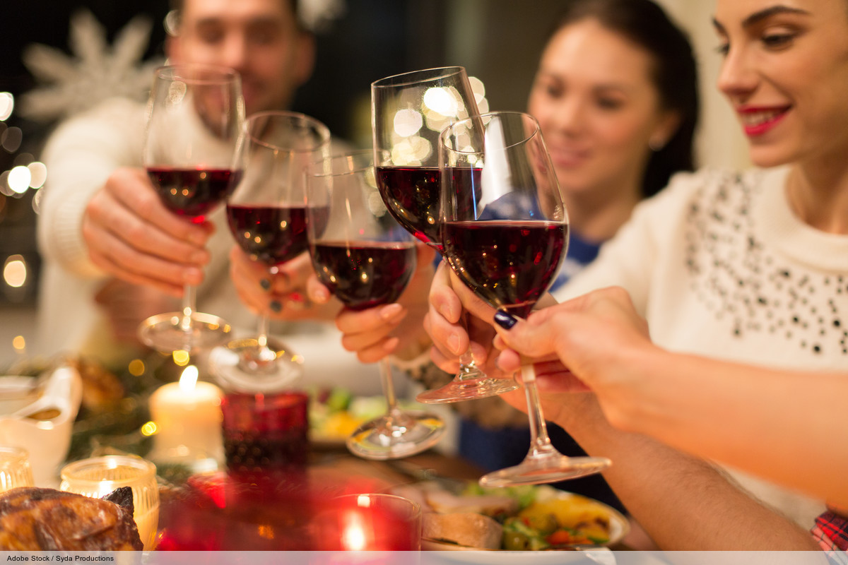 holidays and celebration concept - close up of happy friends having christmas dinner at home, drinking red wine and clinking glasses