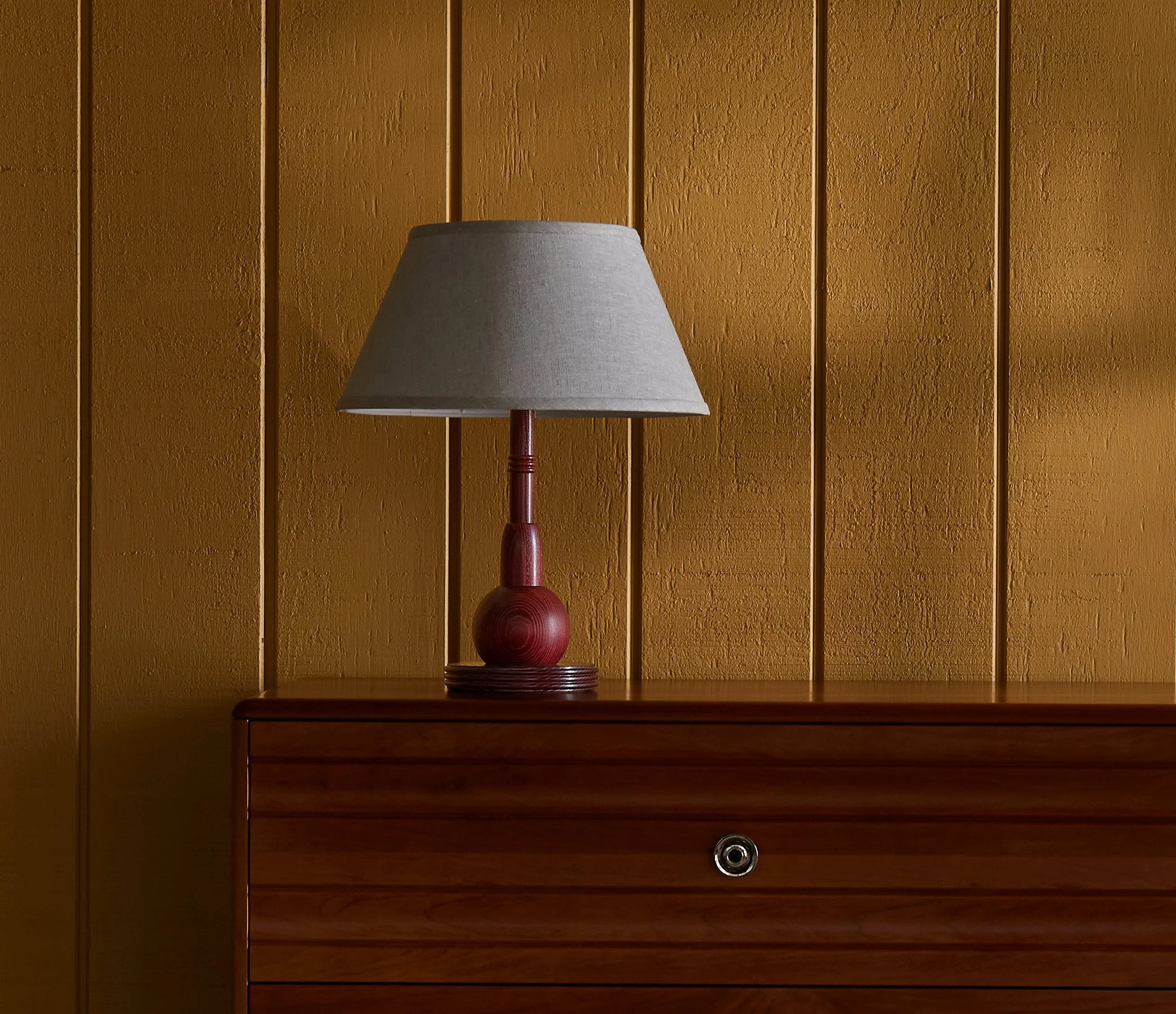 The Neria Lamp is a made-to-order accent table lamp from O&G Studio, crafted in solid hardwood shown here in Oxblood stain on ash atop and O&G Edda Dresser in cherry.