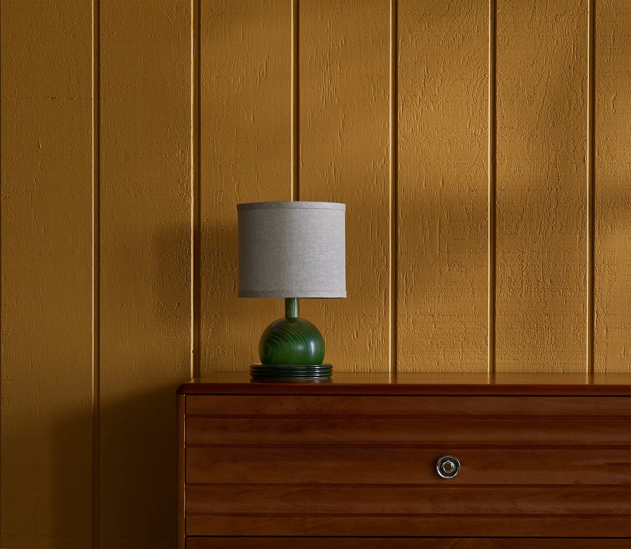 The Iris is an accent lamp from O&G shown here in hunter green stain on ash with a natural linen shade atop an O&G Edda Dresser in solid cherry wood