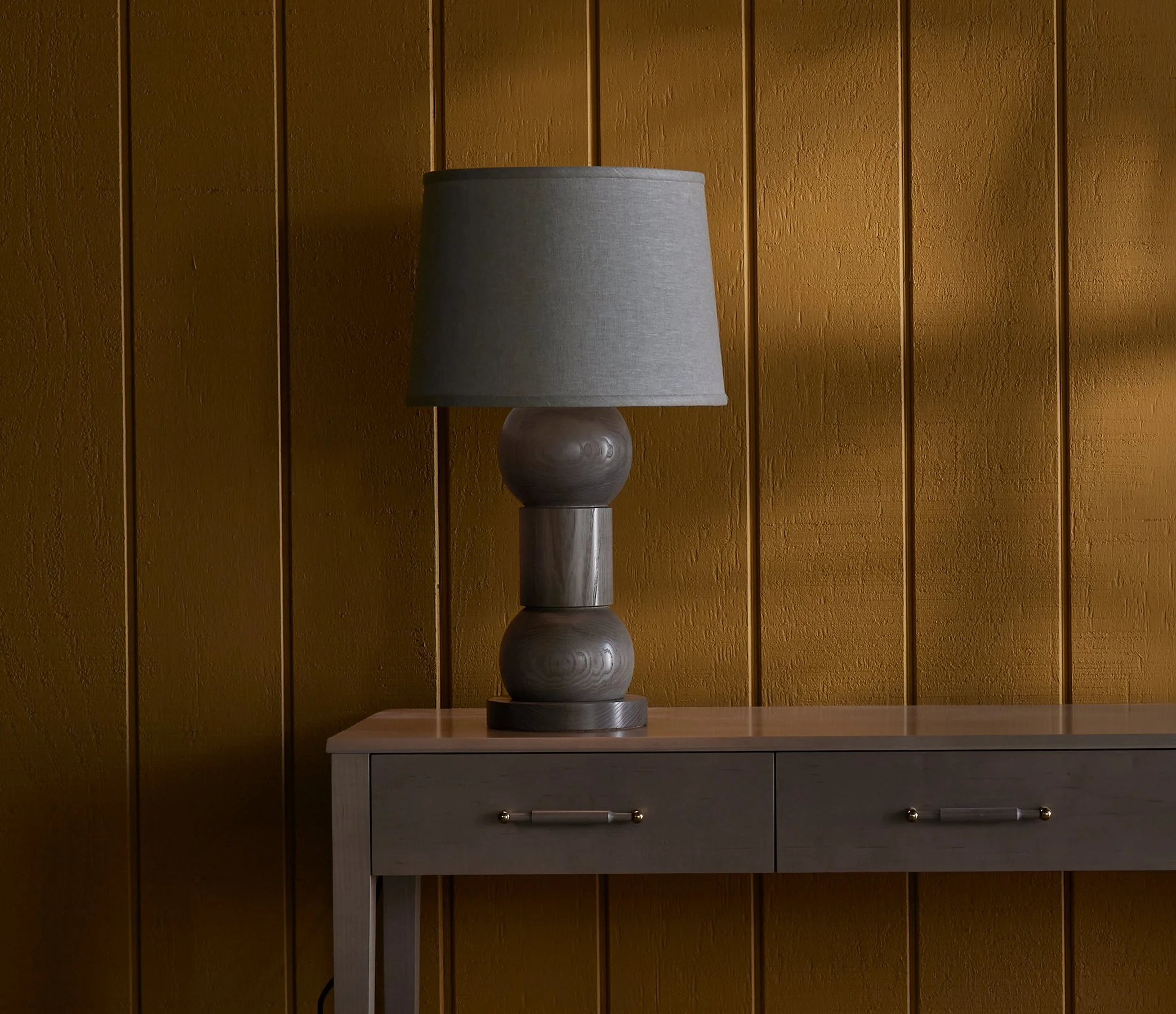 The Orion Lamp is a made-to-order solid hardwood lamp from O&G Studio, shown here in lichen grey stain on ash atop an O&G Atlantic Console in Oyster stain on Maple