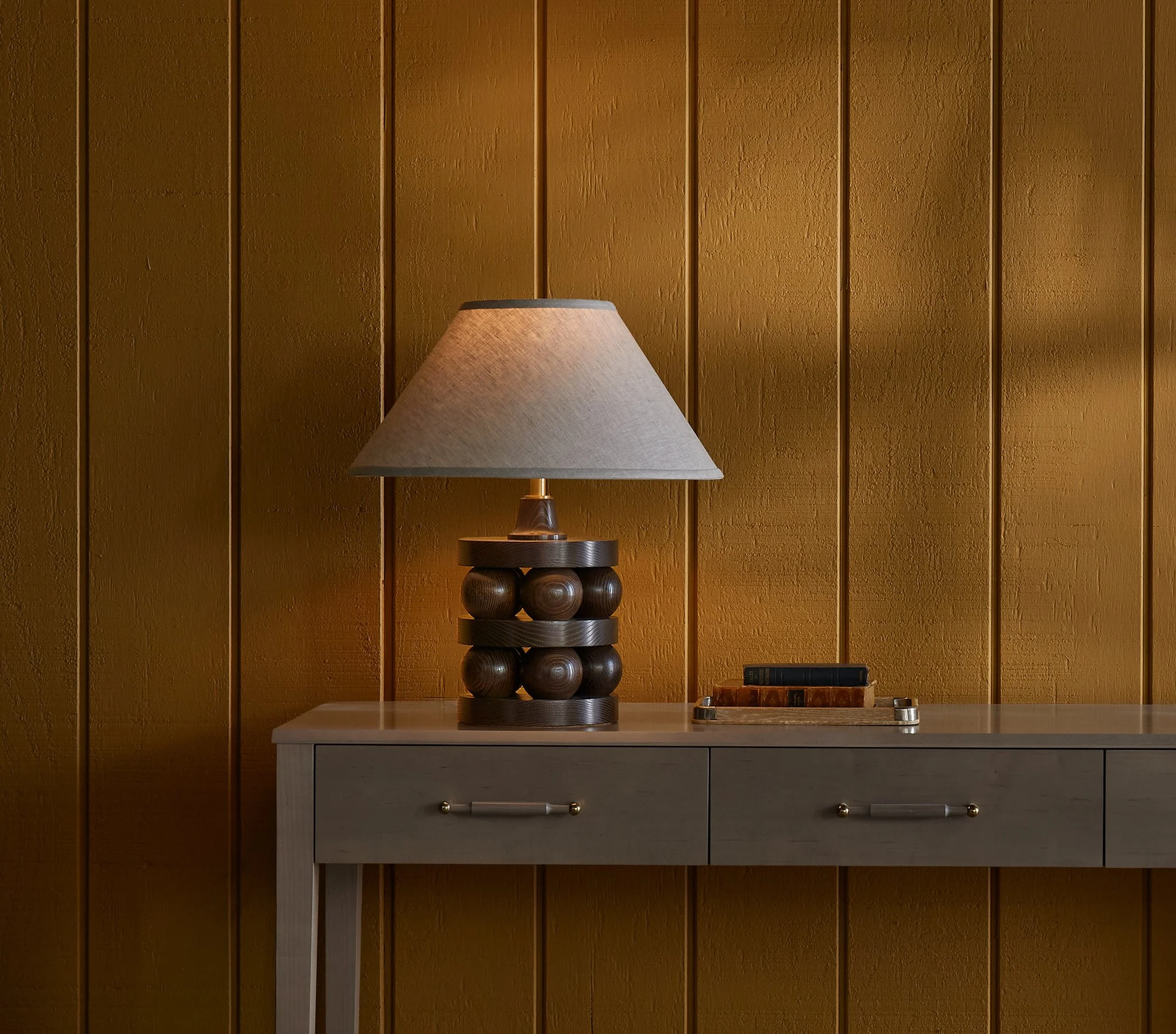 The Lyra is a made-to-order table lamp from O&G Studio availabelin stain finishes on ash, natural walnut and natural cherry. Shown here in Dark Walnut stain on ash atop and O&G Atlantic Console.
