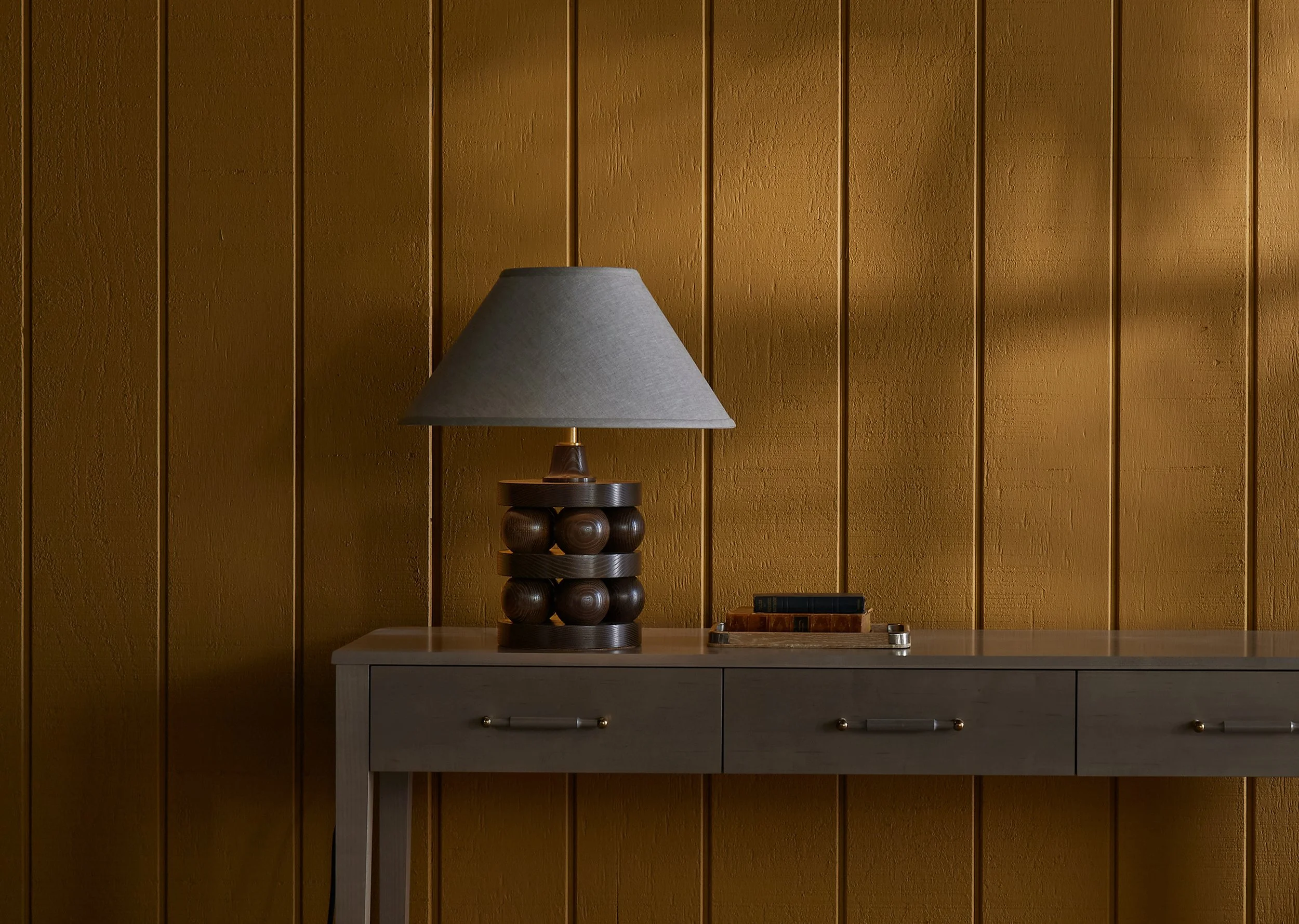 The Lyra is a made-to-order table lamp from O&G Studio availabelin stain finishes on ash, natural walnut and natural cherry. Shown here in Dark Walnut stain on ash atop and O&G Atlantic Console.