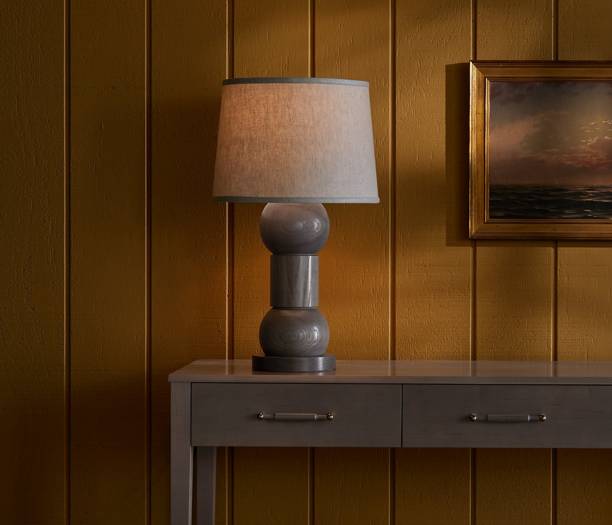 The Orion Lamp is a made-to-order solid hardwood lamp from O&G Studio, shown here in lichen grey stain on ash atop an O&G Atlantic Console in Oyster stain on Maple