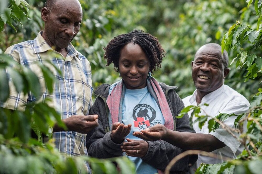 Photo courtesy JoAnne McArthur/Unbound Project. Dr. Gladys Kalema-Zikusoka with coffee farmers inspecting coffee beans grown on the outskirts of Bwindi Impenetrable Forest
