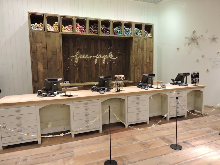  4 point of sale cashwrap with a custom ‘Black Smith Cottage’ backwrap showcasing a built in crate installation of bright yarn filled cubbies.