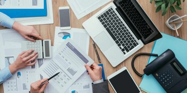 Cluttered-Office-Desk-With-Financial-Papers-And-Computer-Technology-Devices-750x375.jpg