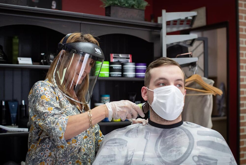 Owner Rosanna Petan wears a face shield and Jack Willis wears a face mask as she cuts his hair at Frank’s Barbershop, in Vancouver, on May 19, 2020. photo: THE CANADIAN PRESS/Darryl Dyck