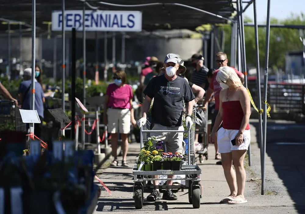 People wait in a line for the cashiers, separated by their carts and a corral made of tape to allow for physical distancing, at a garden centre in Ottawa on May 23, 2020. photo: THE CANADIAN PRESS/Justin Tang