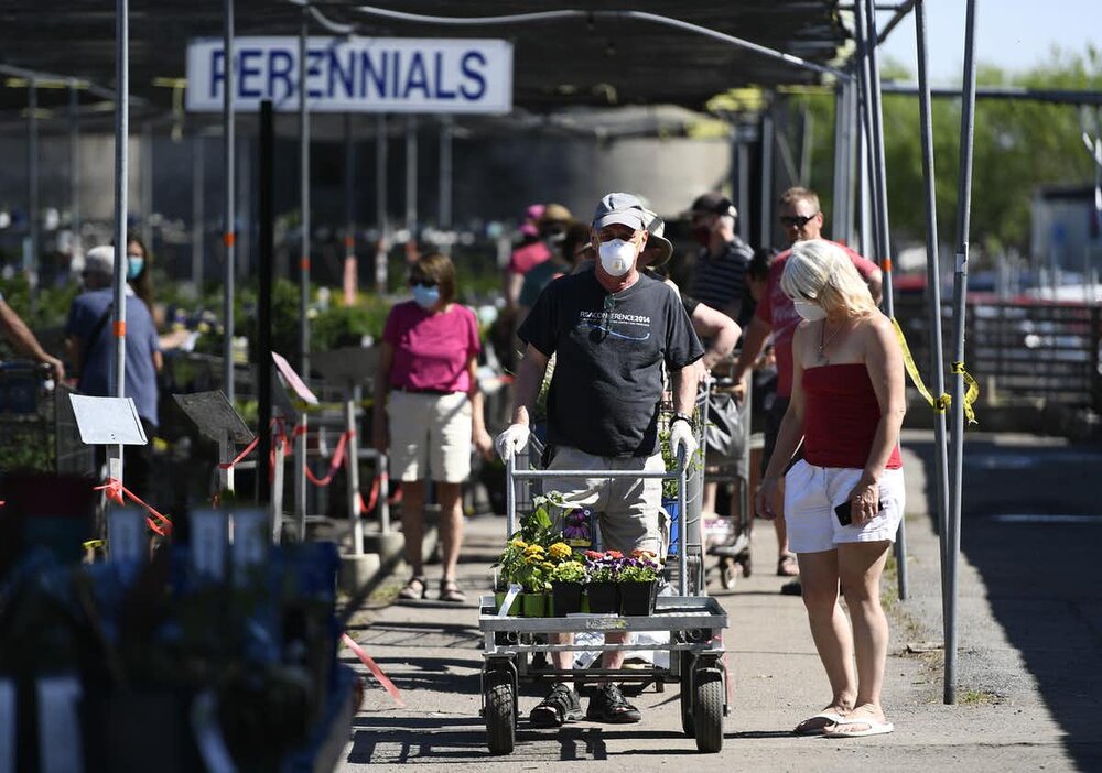 People wait in a line for the cashiers, separated by their carts and a corral made of tape to allow for physical distancing, at a garden centre in Ottawa on May 23, 2020. photo: THE CANADIAN PRESS/Justin Tang