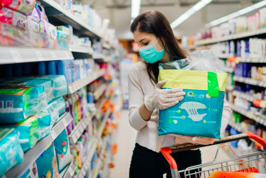 Female shopper with facial mask loads shopping cart. Source: DepositPhotos