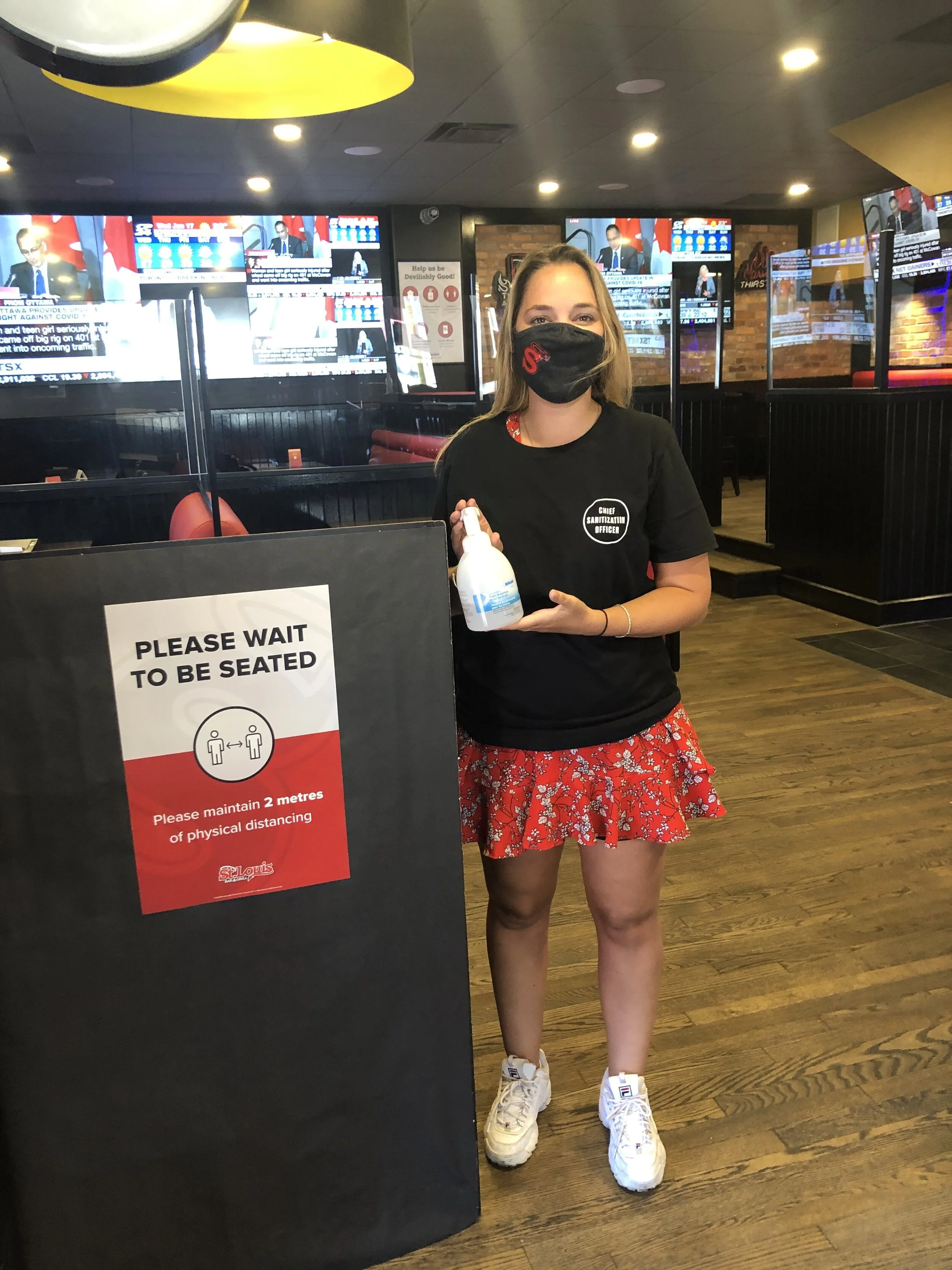   CHIEF SANITIZATION OFFICER HOLDING ANTI-BACTERIAL SPRAY AT THE HOSTESS STAND. PHOTO: ST. LOUIS  