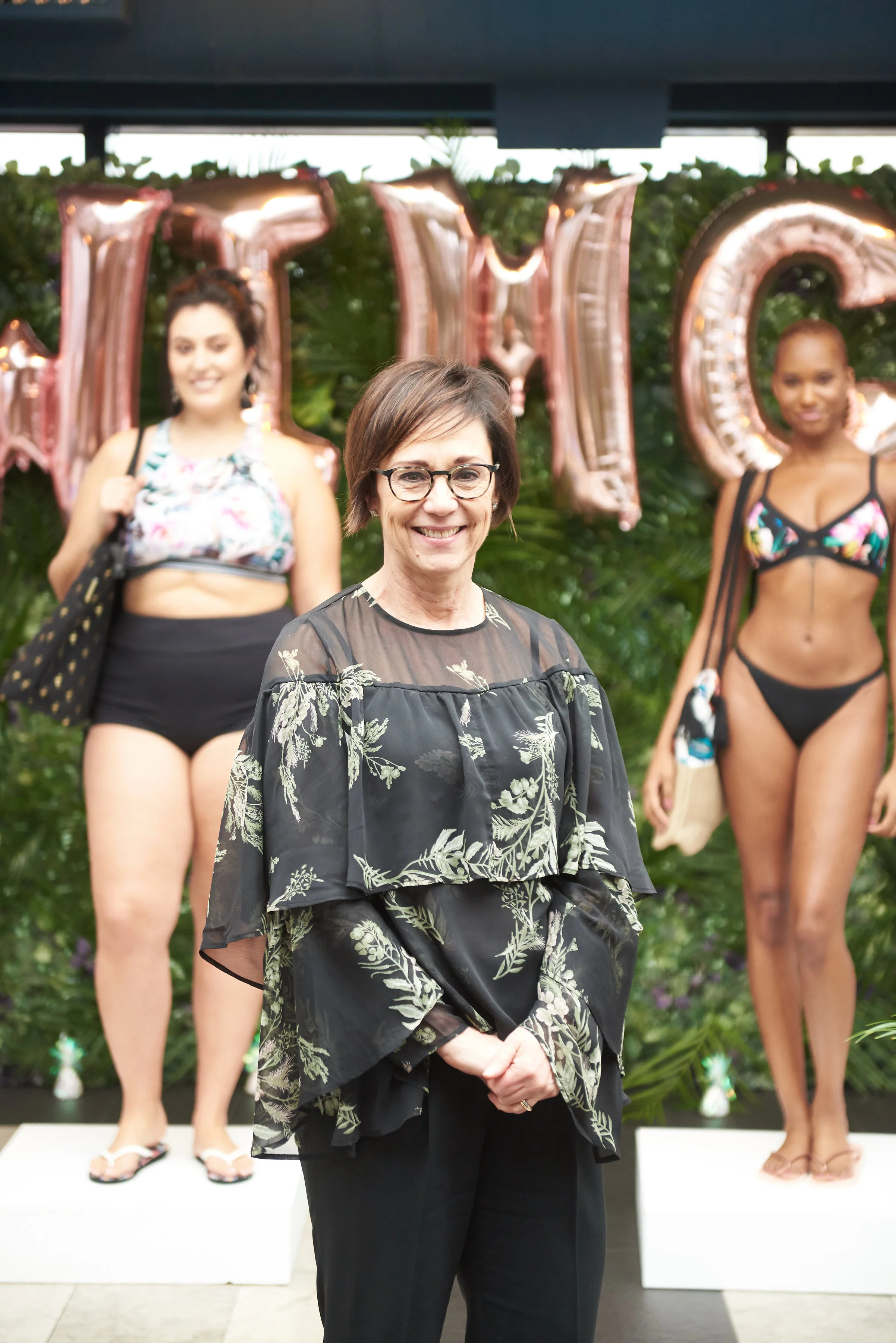 photo of lori bacon standing in front of two women modelling swimco.