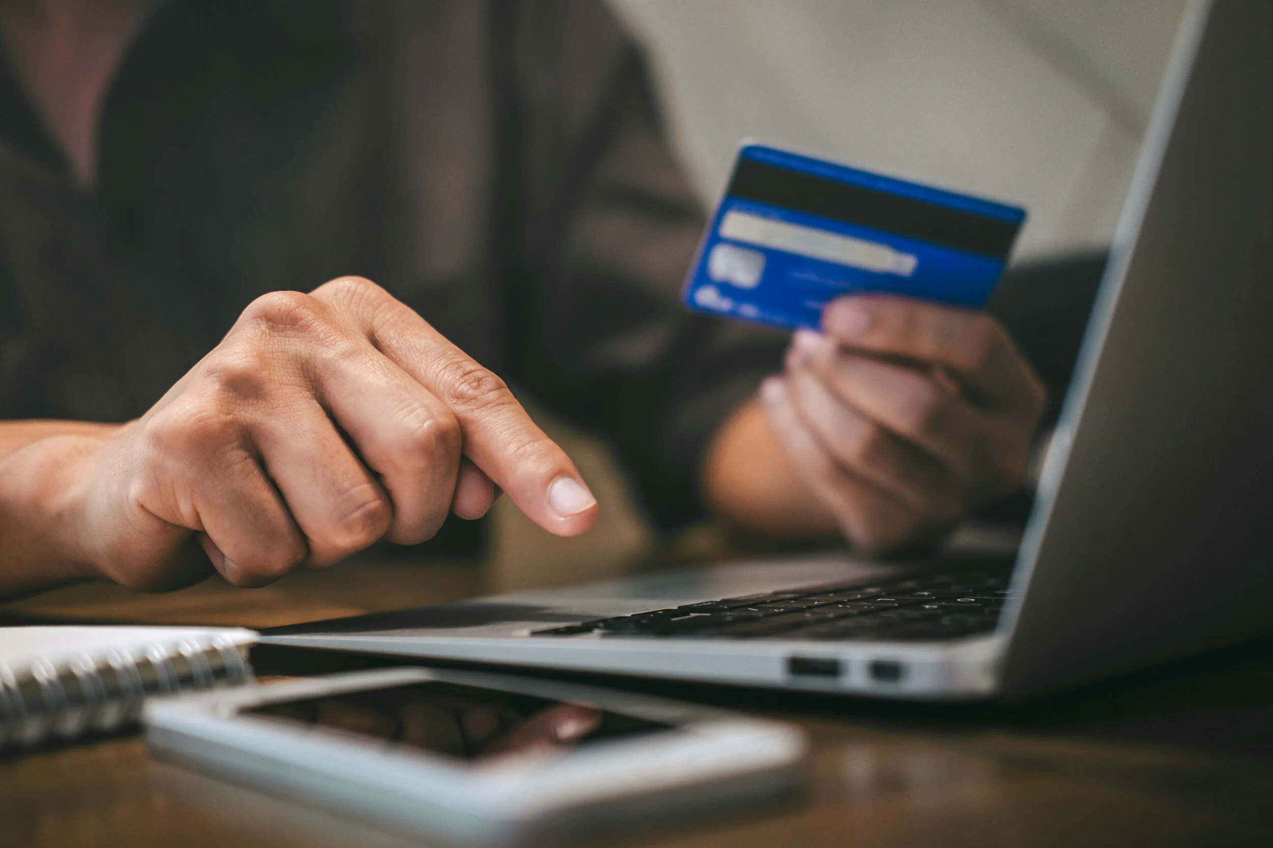 person using credit card and laptop to shop online