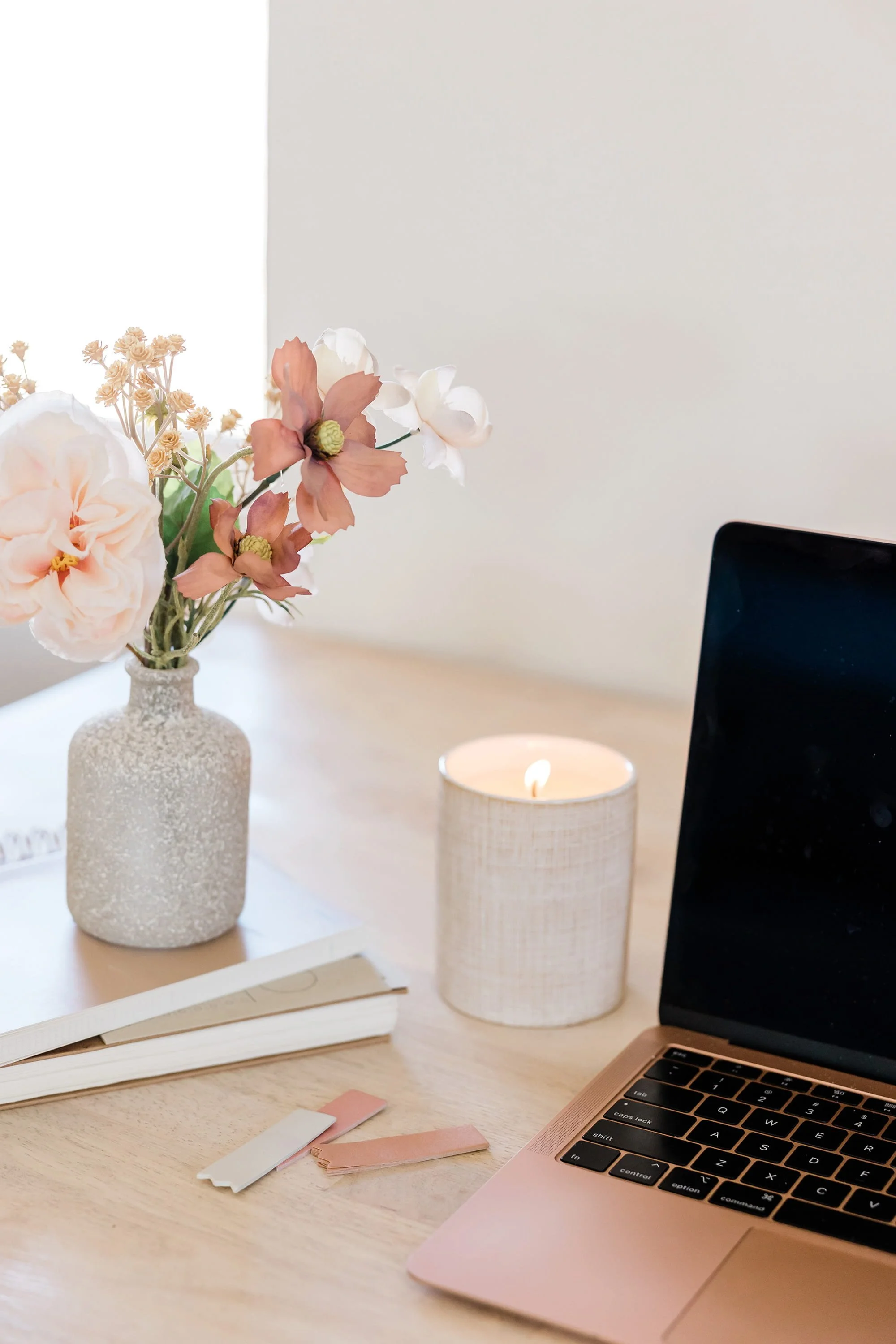 Image of a desk top with an open laptop and burning candle