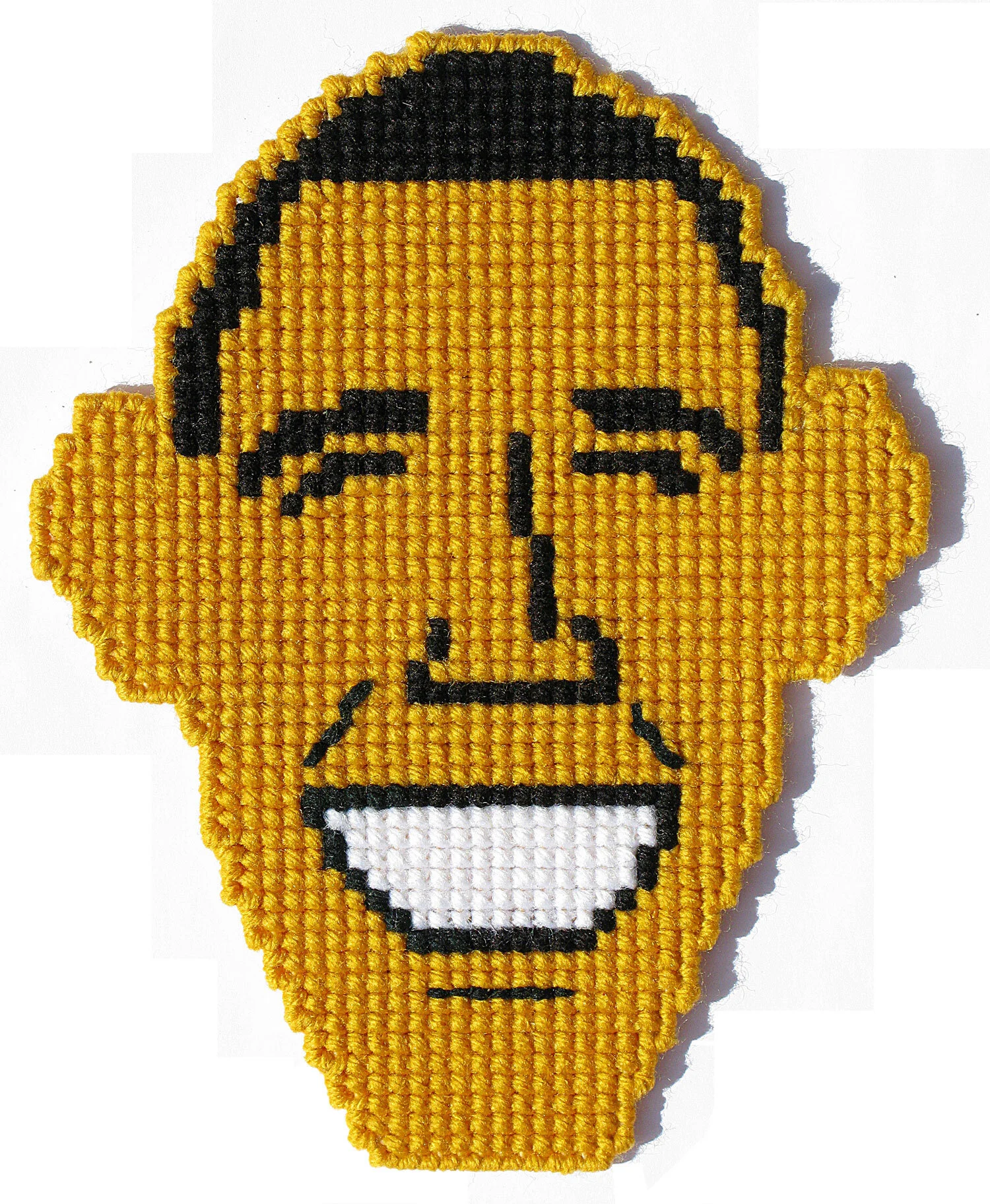 Cross-stitch art of a smiling face with closed eyes and short dark hair on a yellow background.