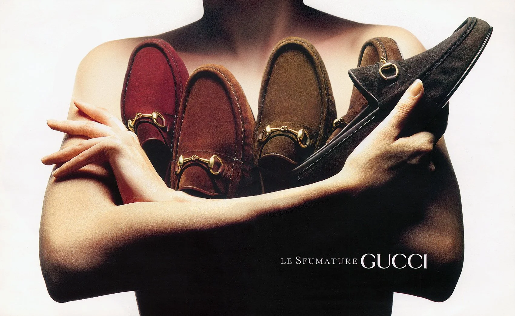 Advertising design for classic Gucci horse bit loafers featuring a nude female figure with an armful of shoes. The figure is silhouetted on a white background with a tagline written in Italian to the left of the Gucci word mark reversed against the s