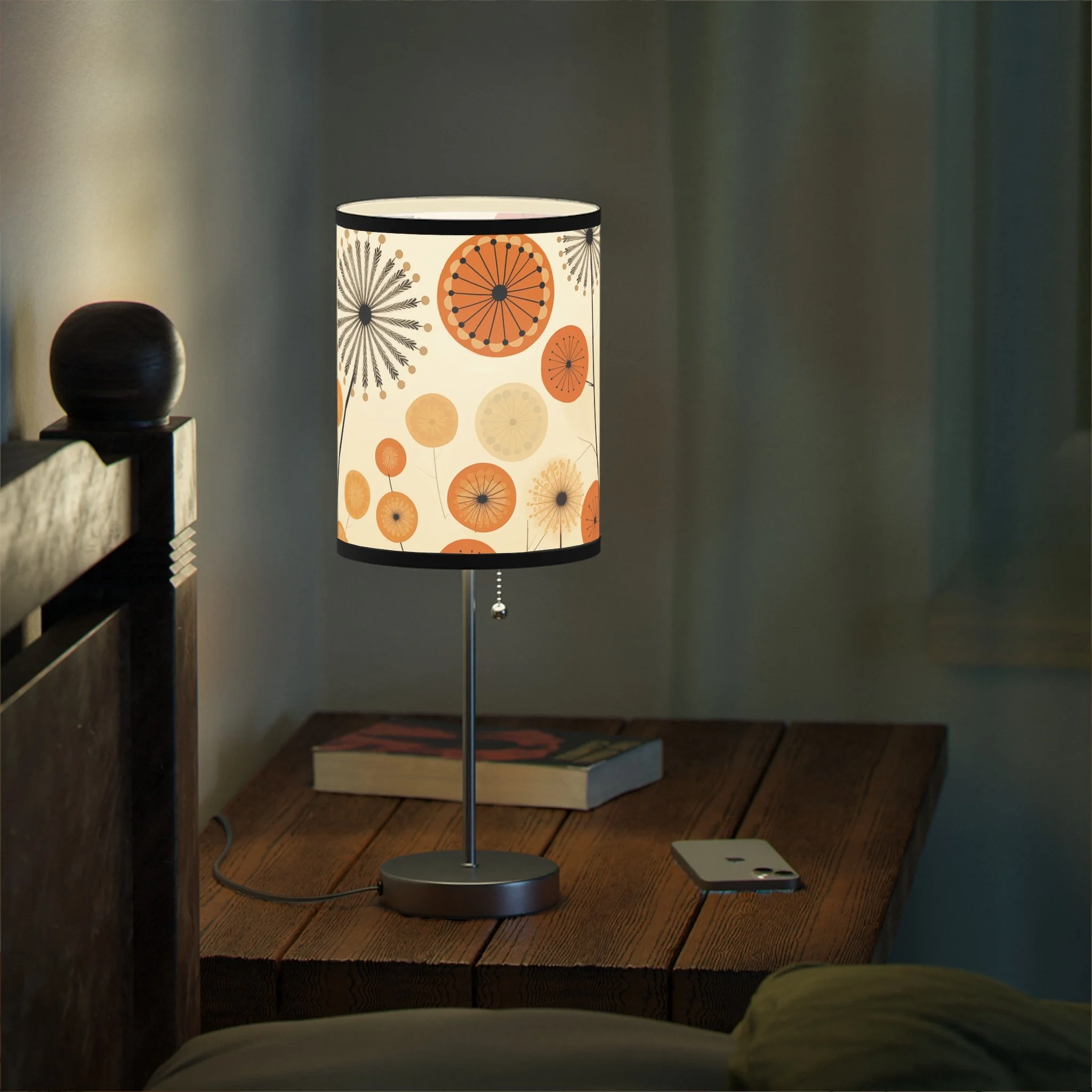 A table lamp with a floral pattern of orange and beige dandelions, placed on a wooden table.