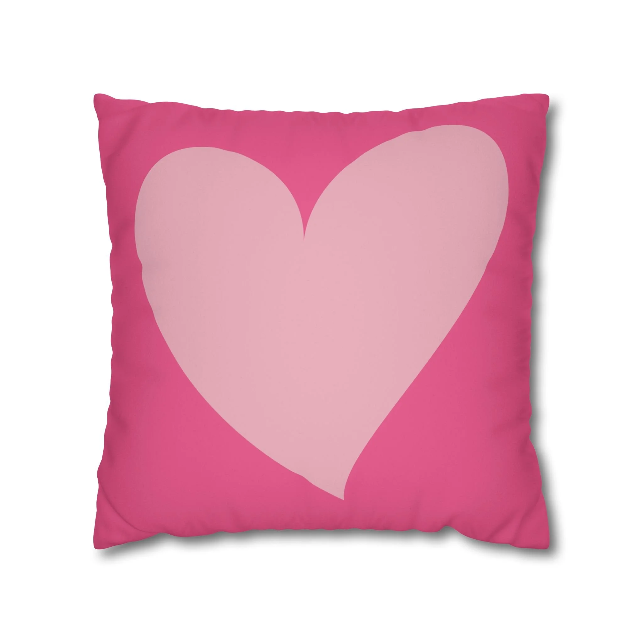 Pink throw pillow with a large light pink heart design in the center.