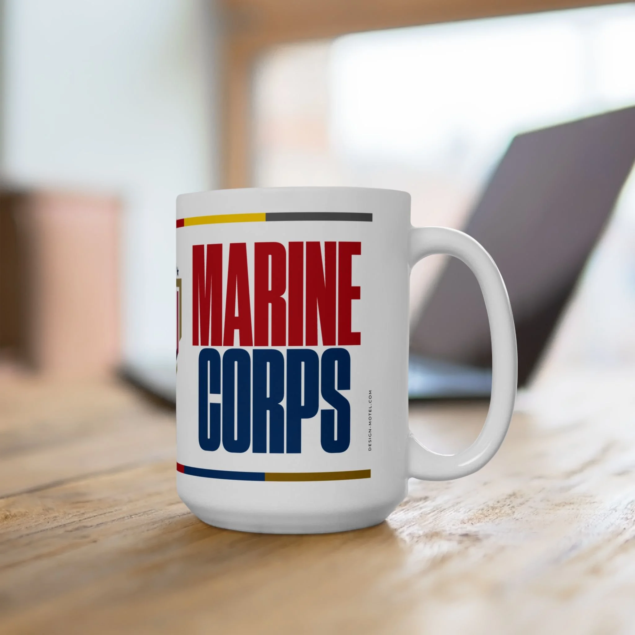 White coffee mug with bold red and blue text that says "Marine Corps" on a wooden table.